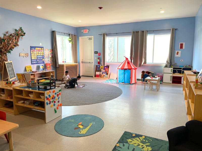 Two children playing on a rug in a classroom