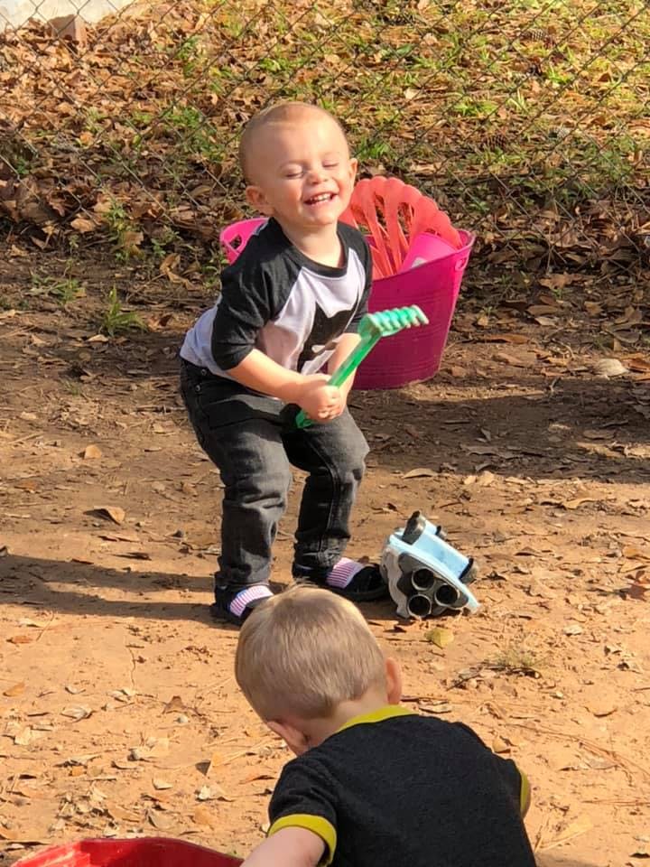 Child holding a green rake, another child in foreground