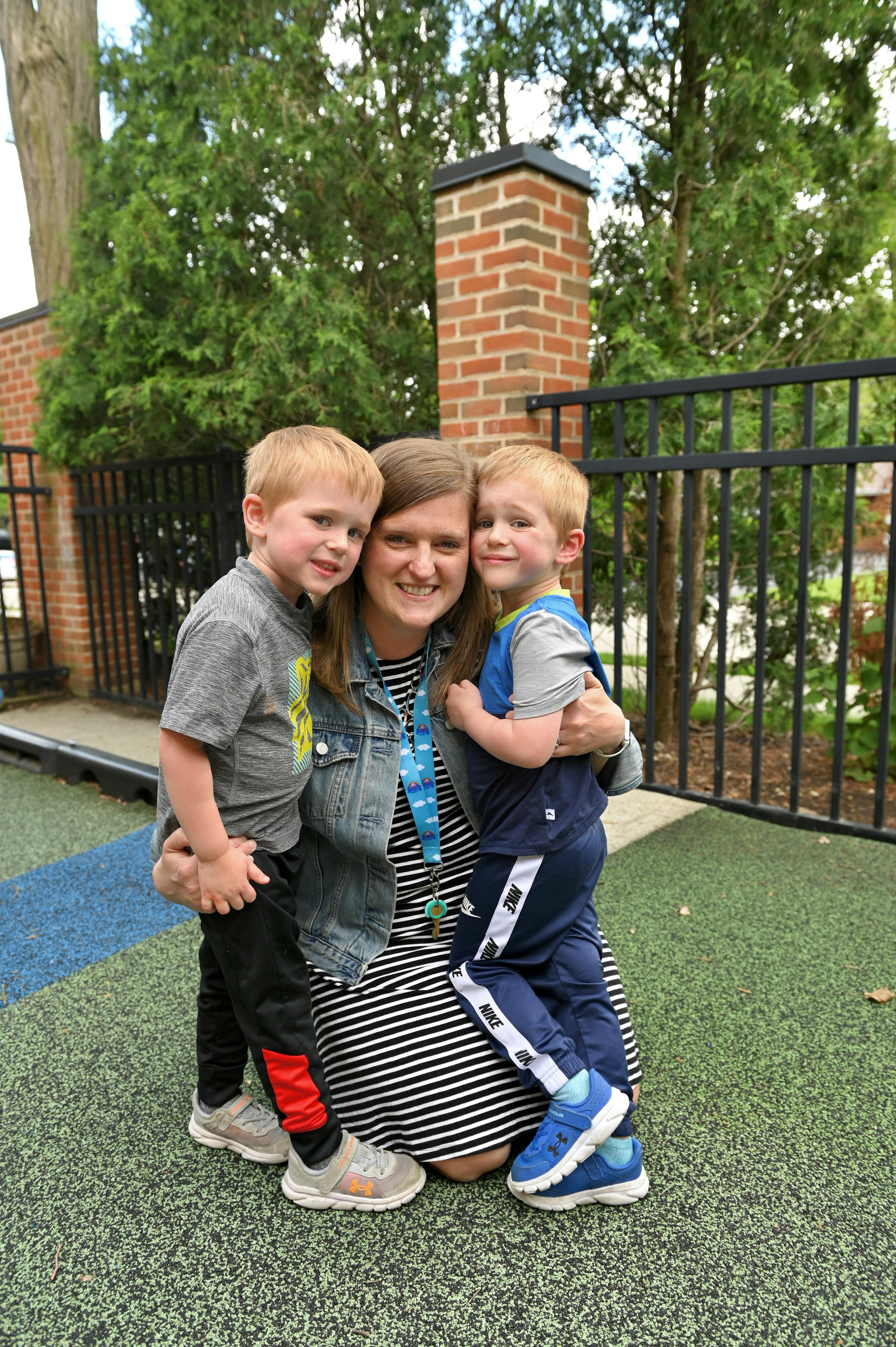 Person kneeling and hugging two children