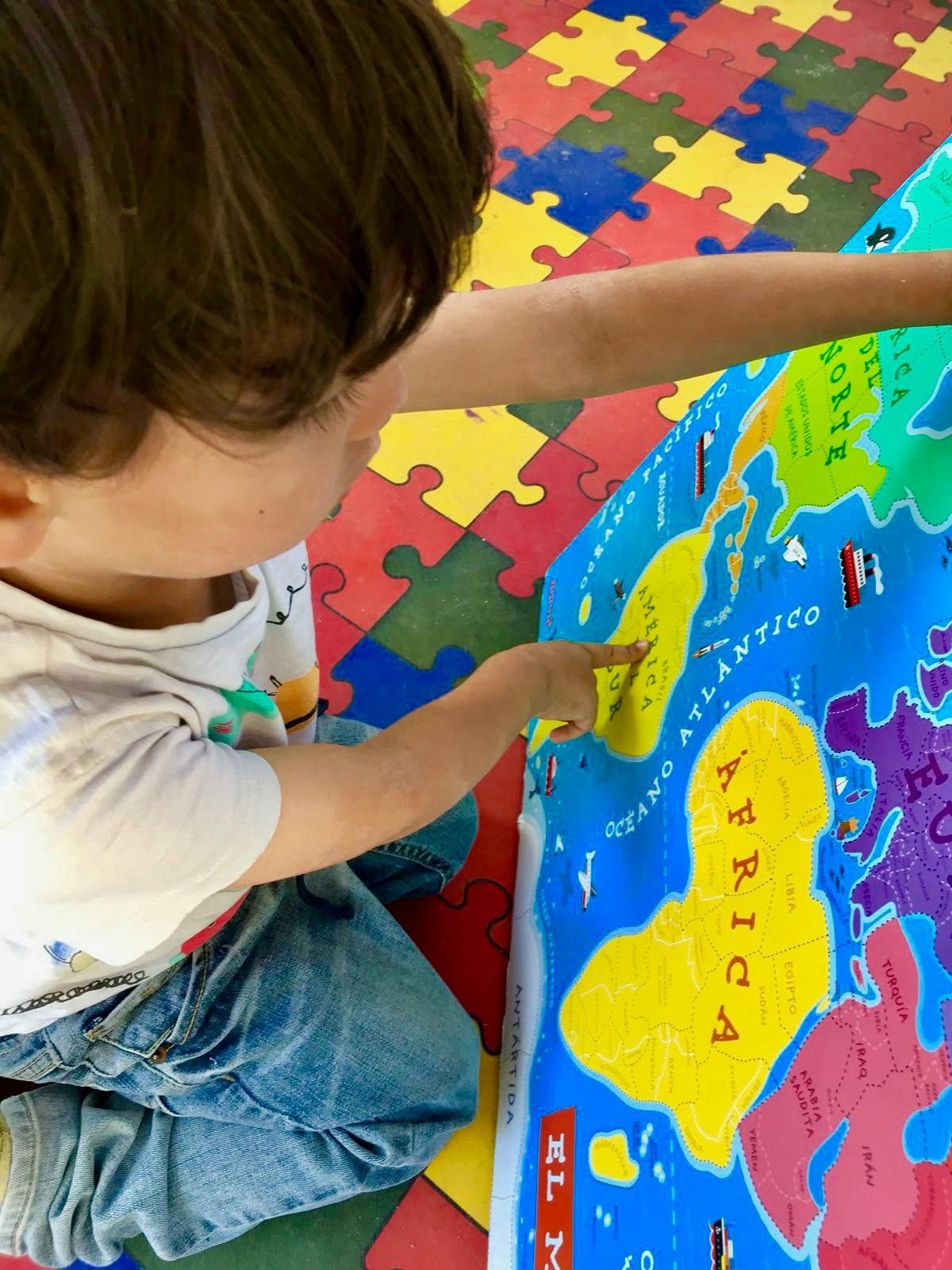Child pointing at a map of the world