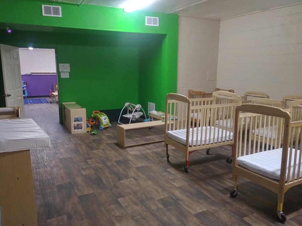 Room with multiple cribs and play items