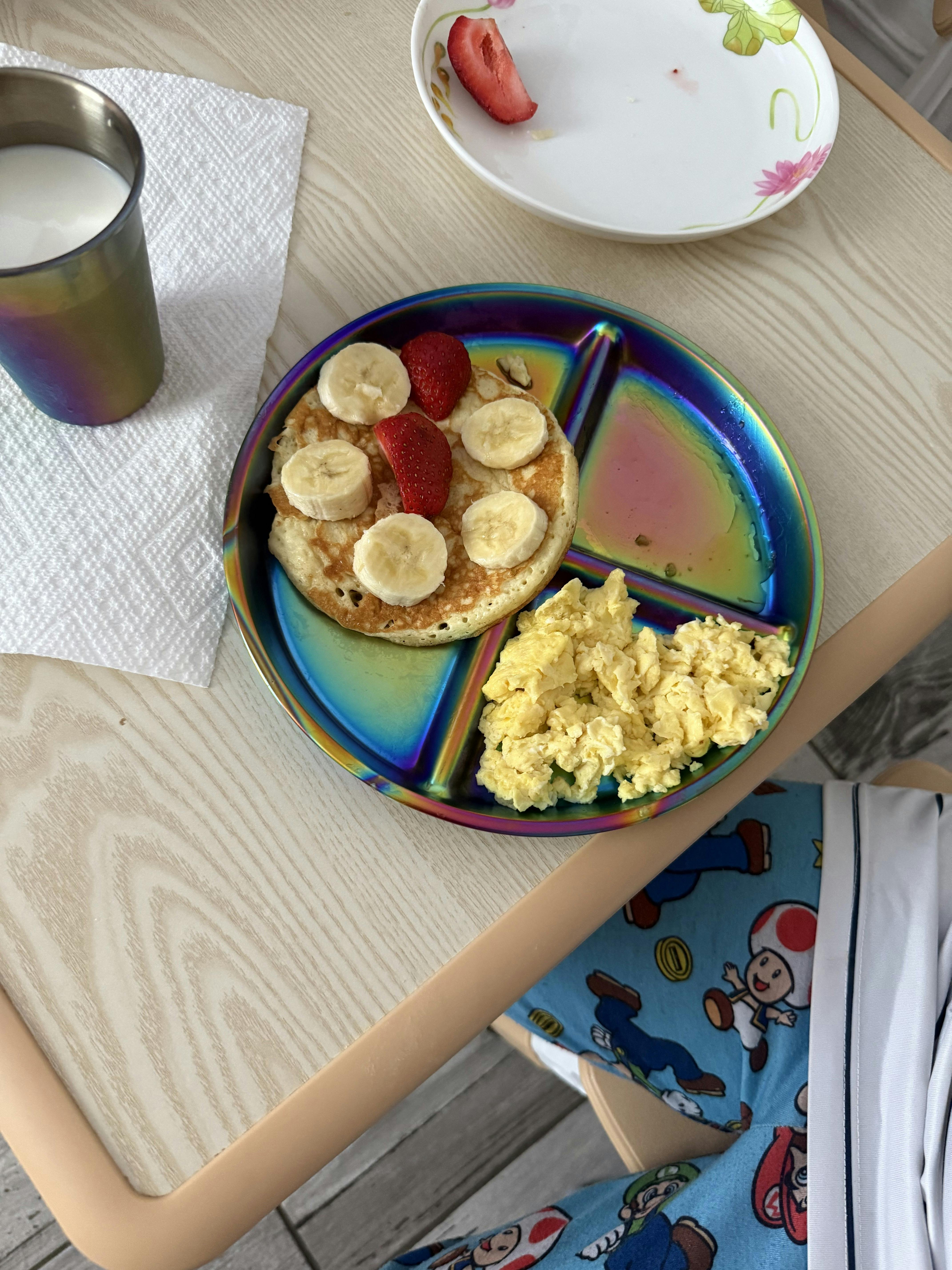 Pancake with banana slices and strawberries served with scrambled eggs