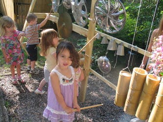 Child playing with a bamboo instrument, other children in background