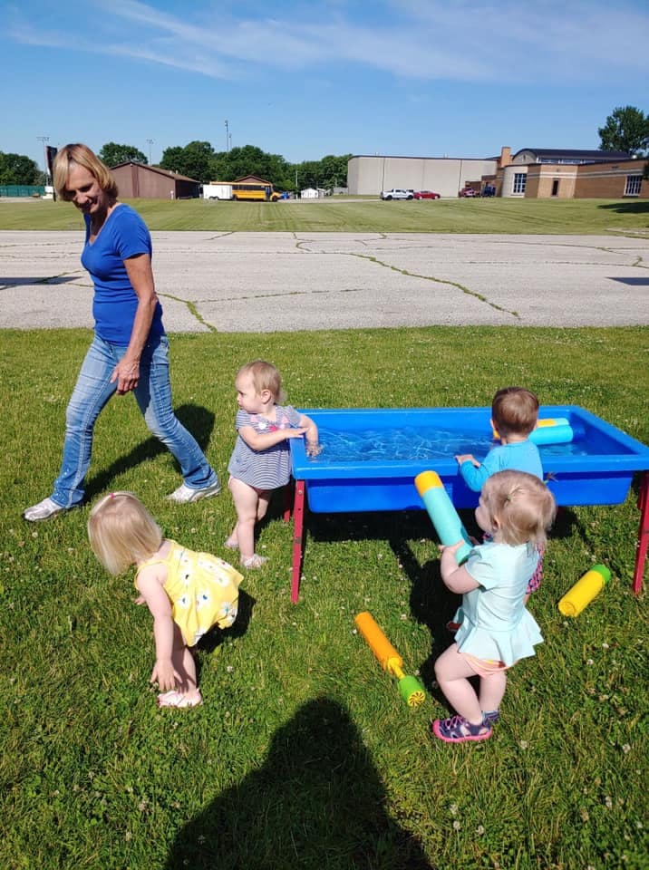 Adult and children playing with a water table outdoors