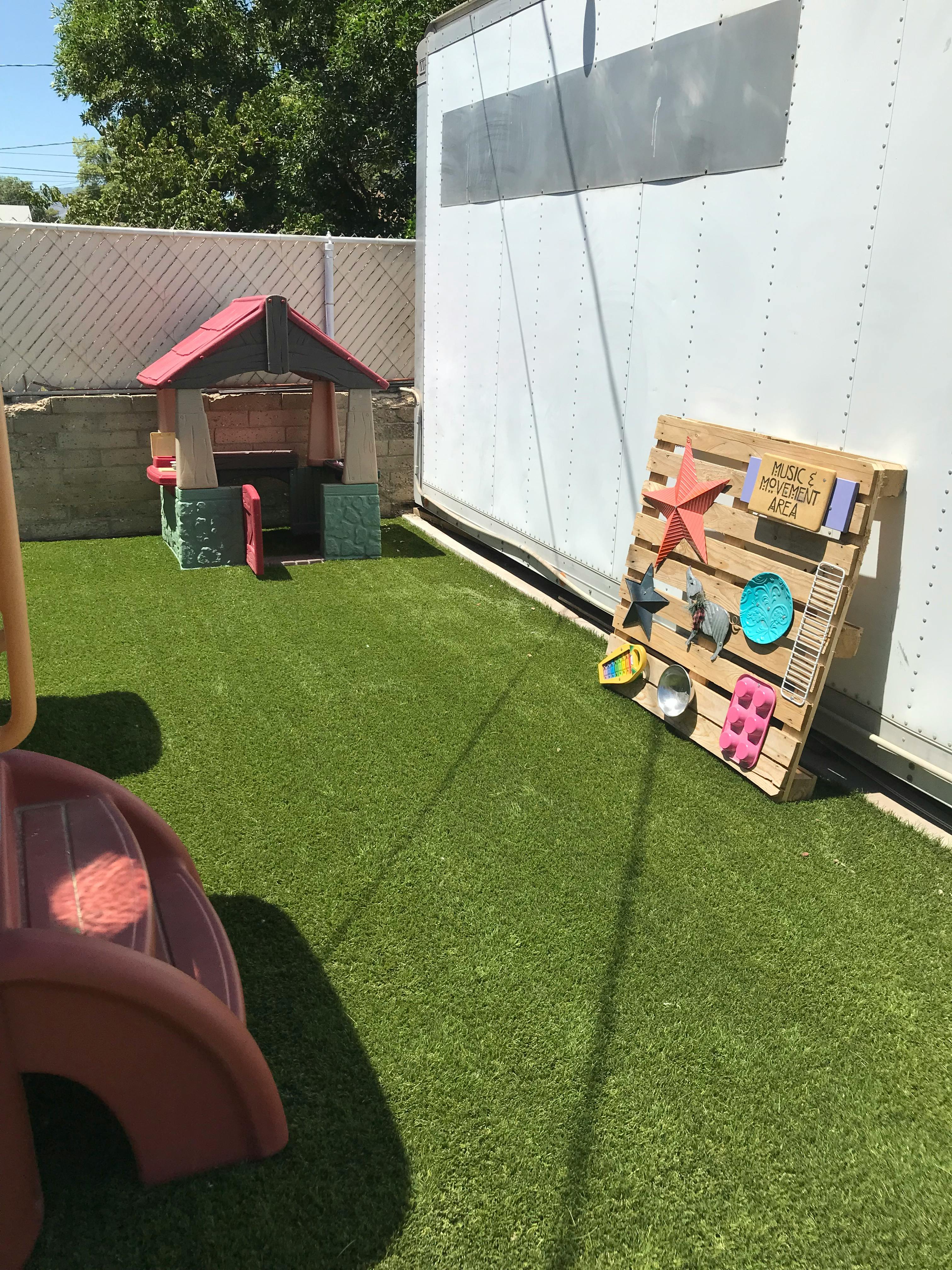 Playhouse and pallet with various items on artificial turf