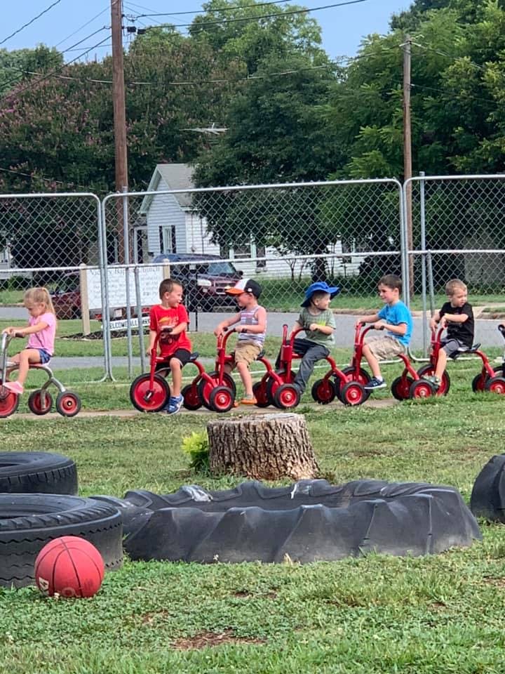 Children riding tricycles on grass