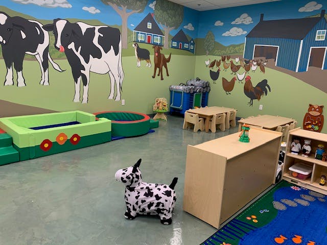 Playroom with farm animal murals, small tables, and a spotted dog toy