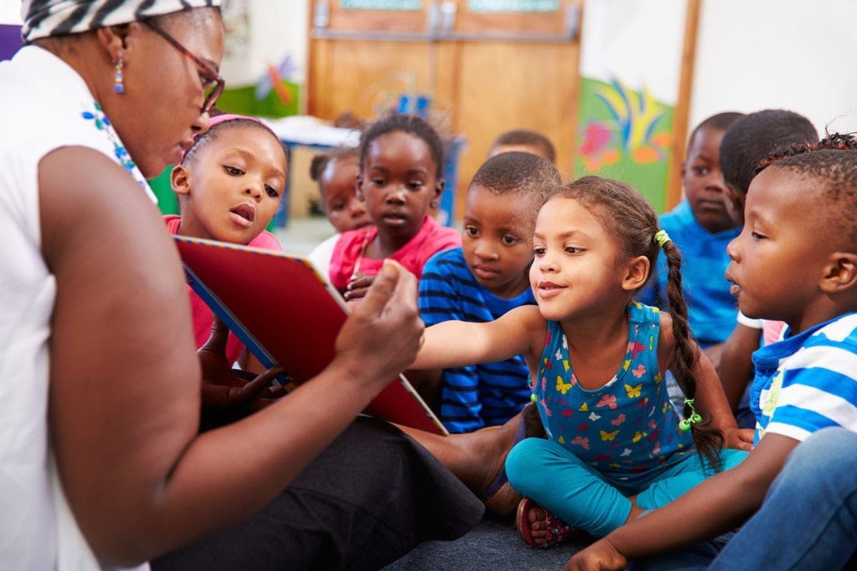 Adult reading a book to a group of children