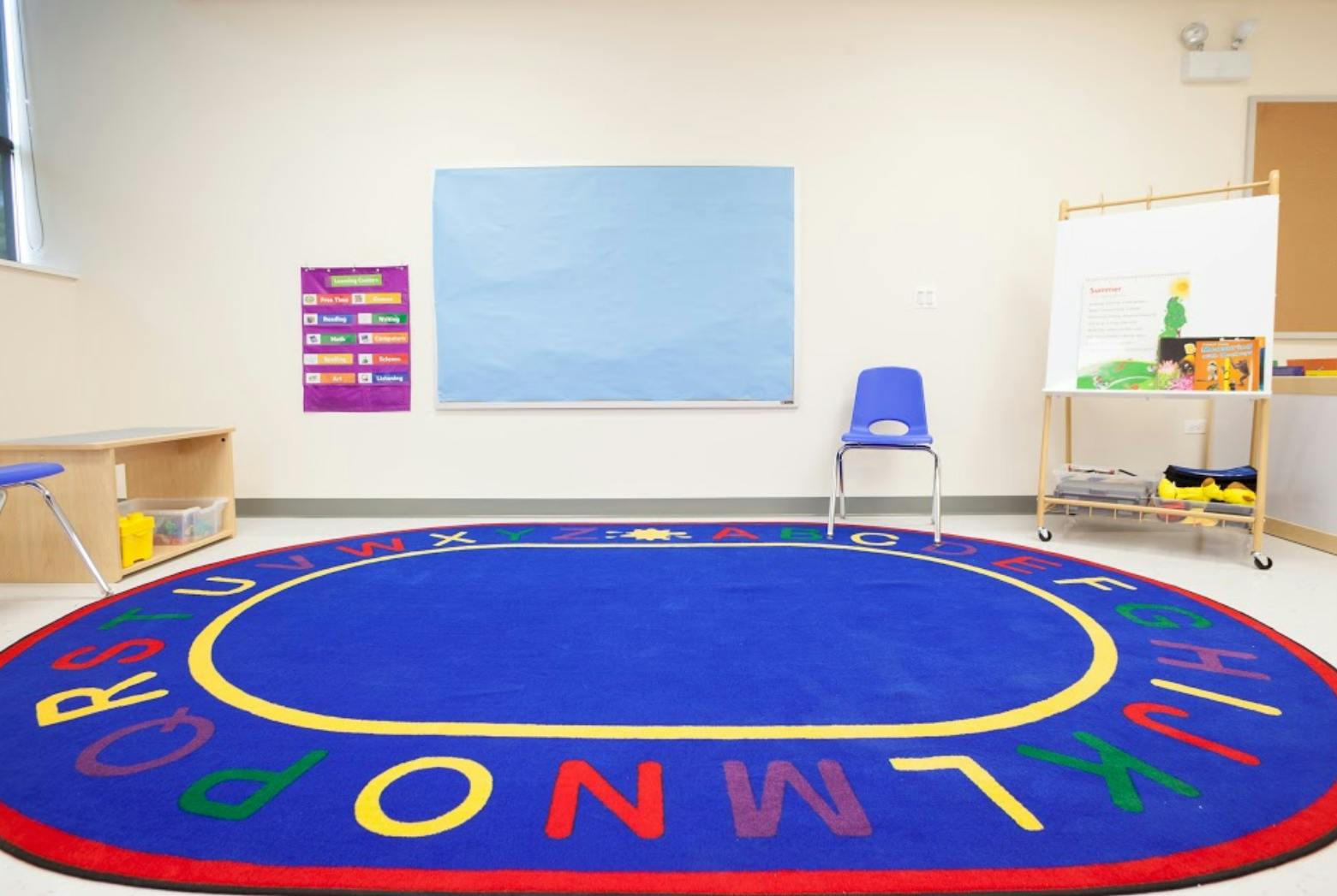 Classroom with an alphabet rug, blue board, and whiteboard