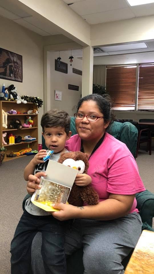 Person holding a child with a stuffed animal and a card