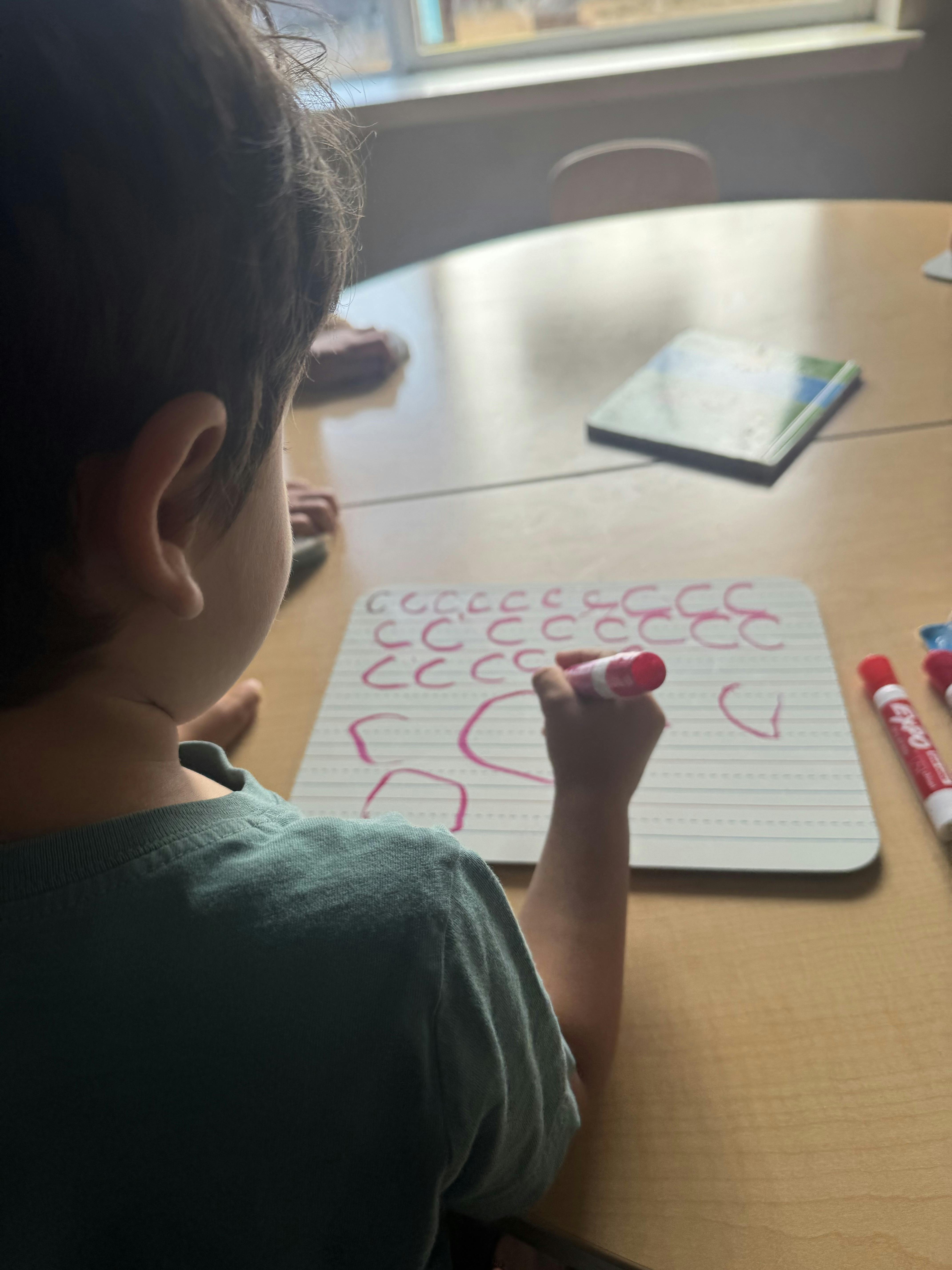 Child practicing writing letters on a whiteboard