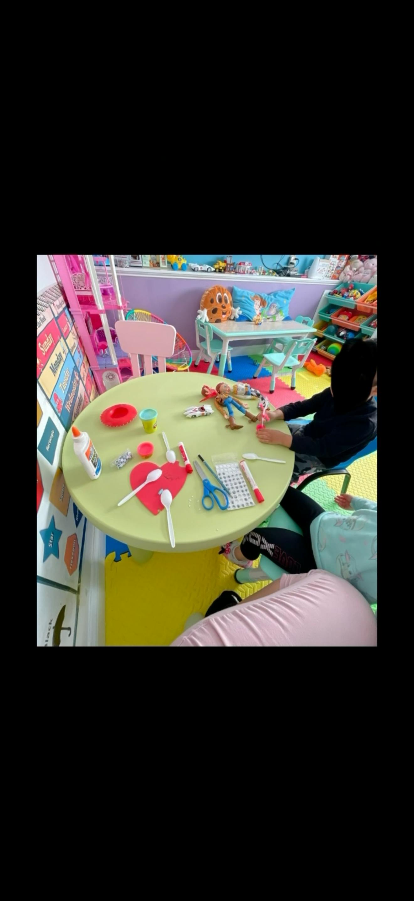 People doing crafts at a small table in a playroom
