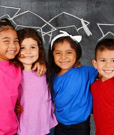 Four children smiling with arms around each other