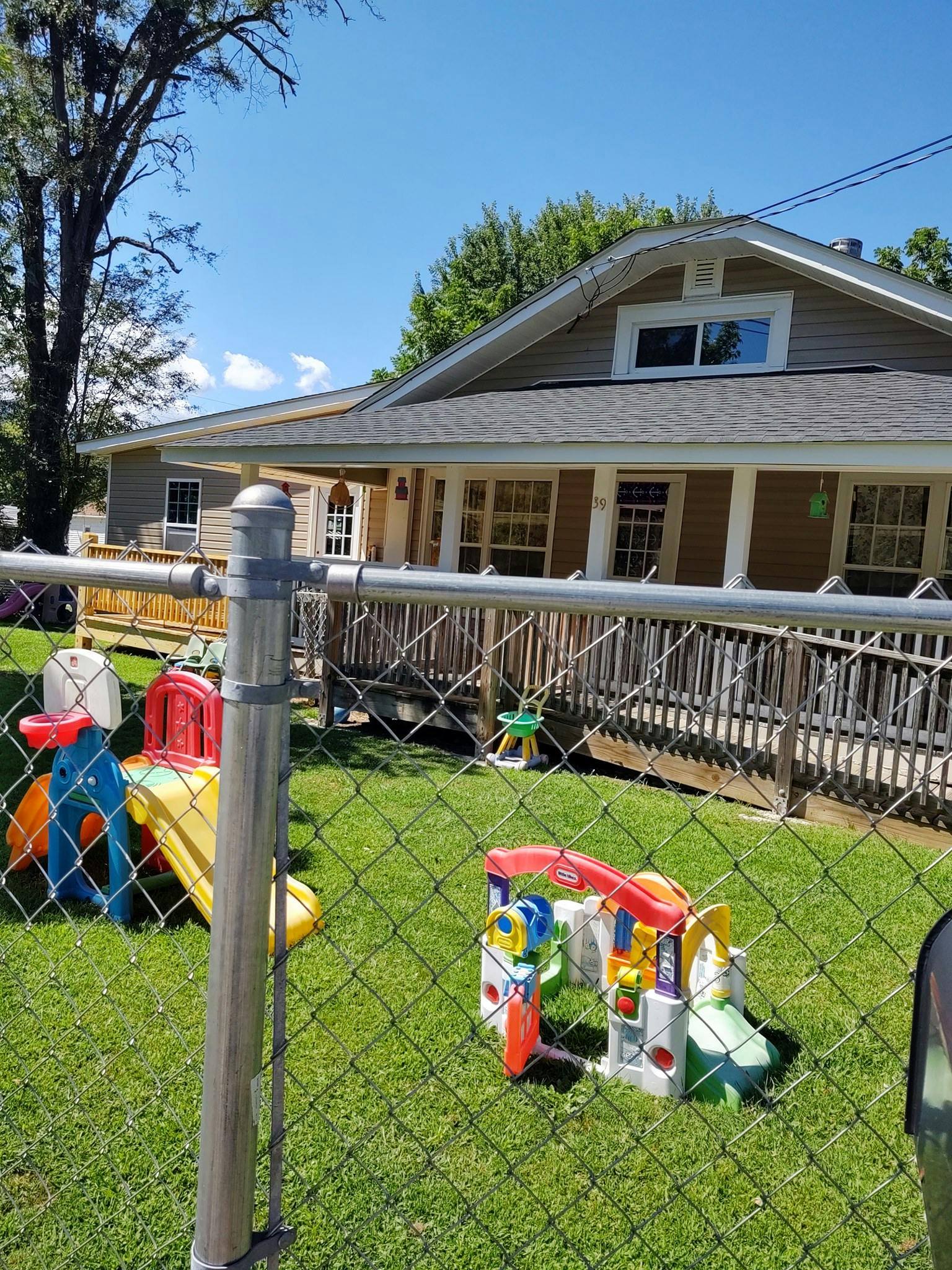 Playground equipment in a fenced yard in front of a house