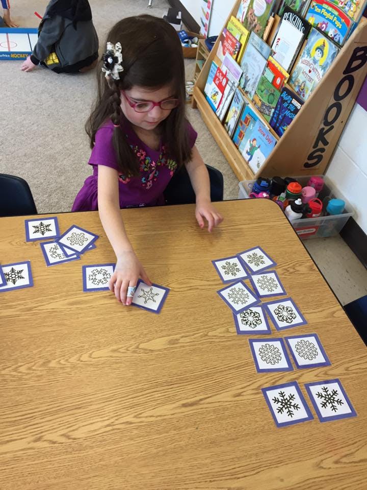 Child playing with snowflake cards at a table