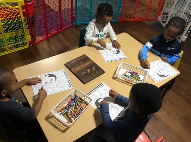 Four children coloring at a table in a classroom