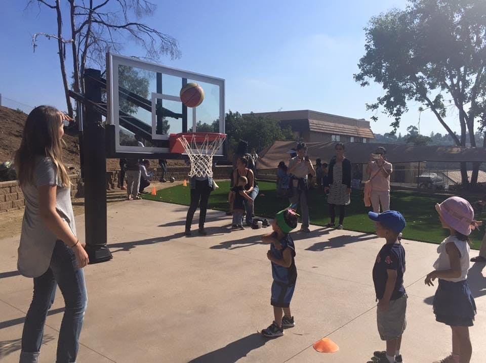 People and children playing basketball outdoors