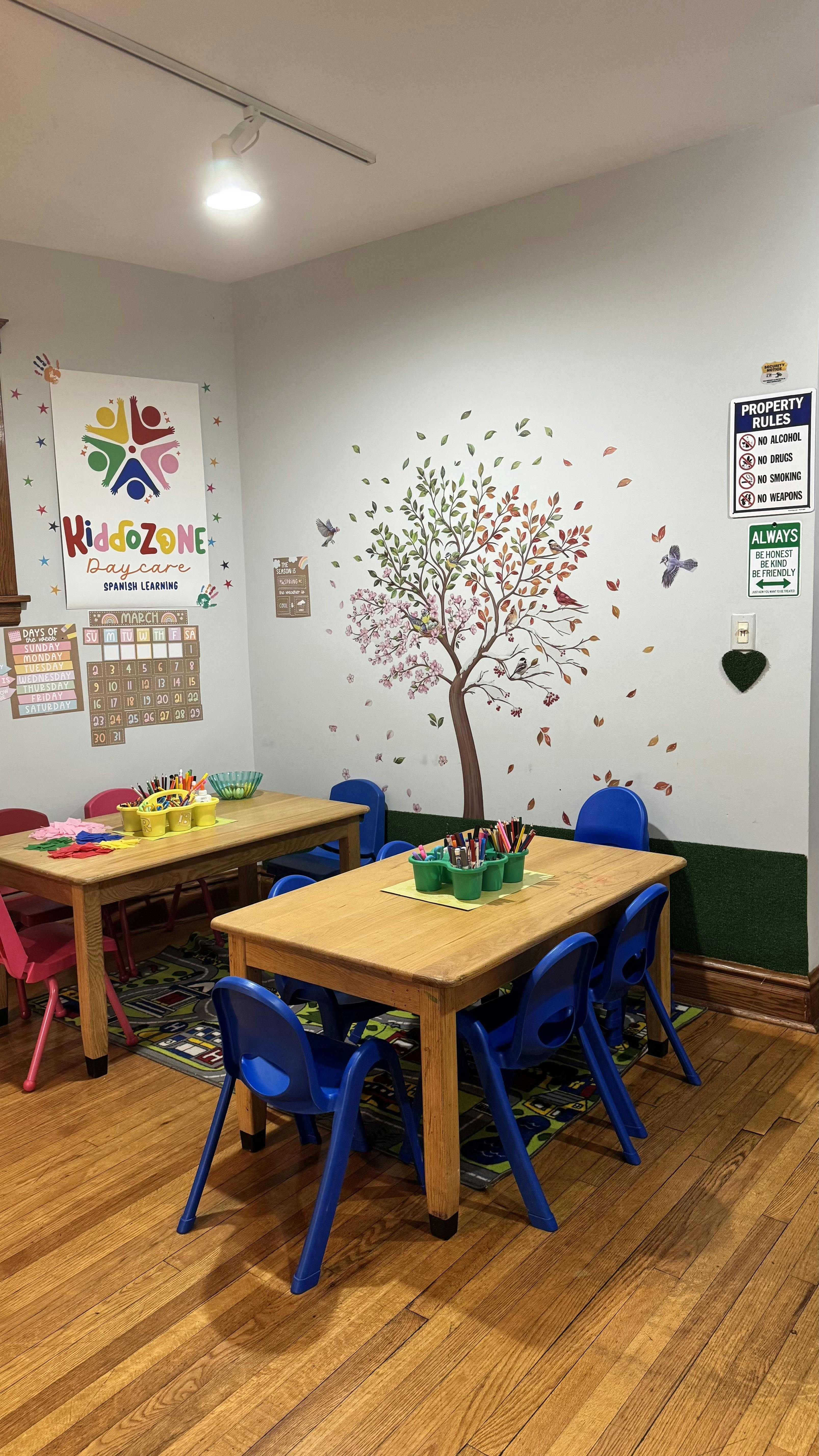 Childcare classroom with two wooden tables and blue chairs