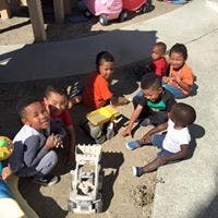 Group of children playing with toy trucks in sand