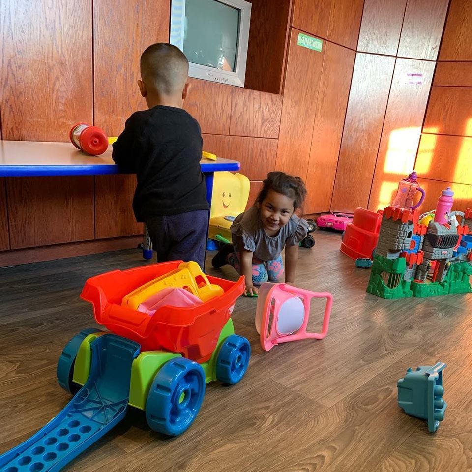 Two children playing with toys on a wooden floor