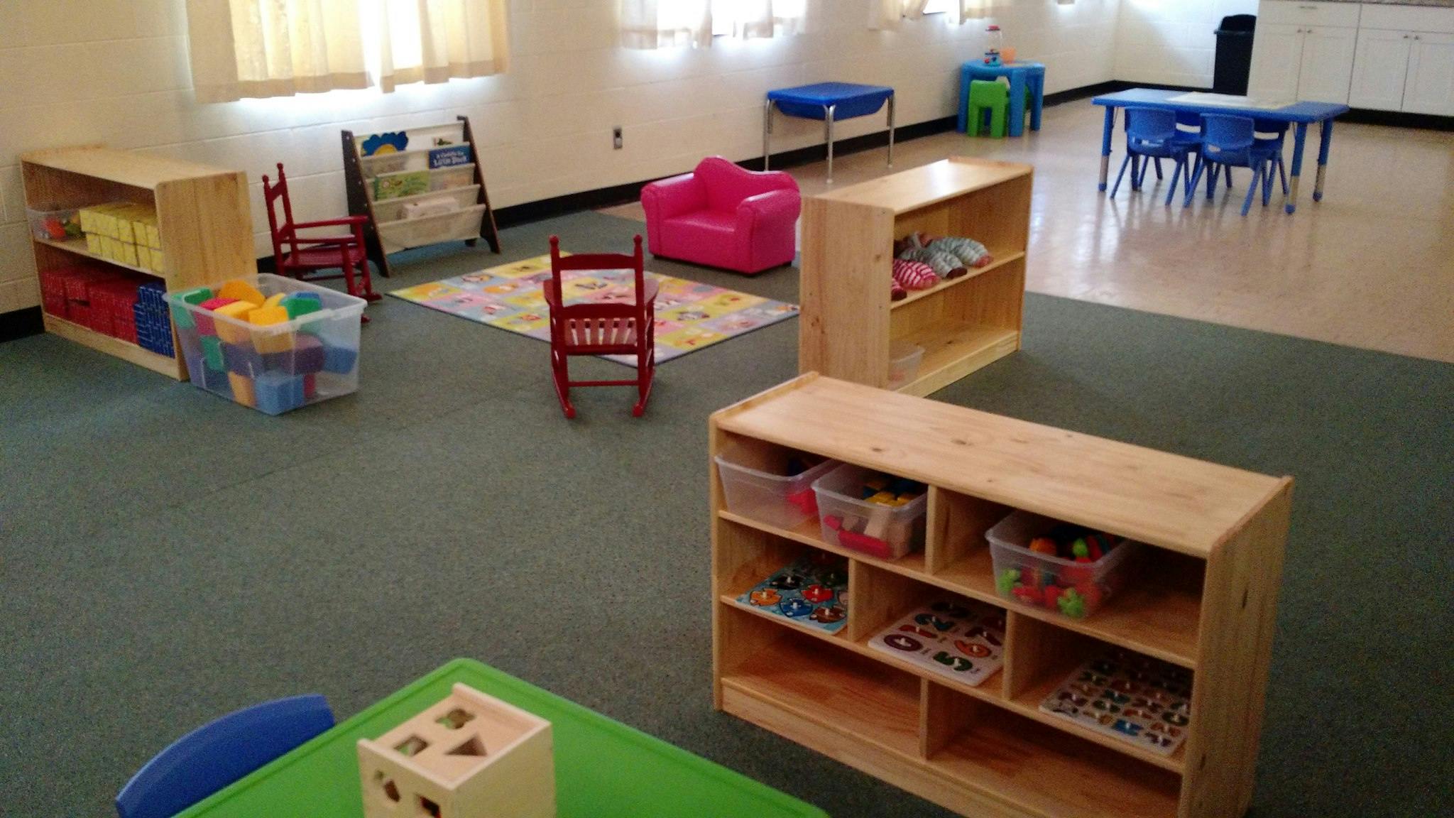 Playroom with small chairs, tables, and shelves with toys