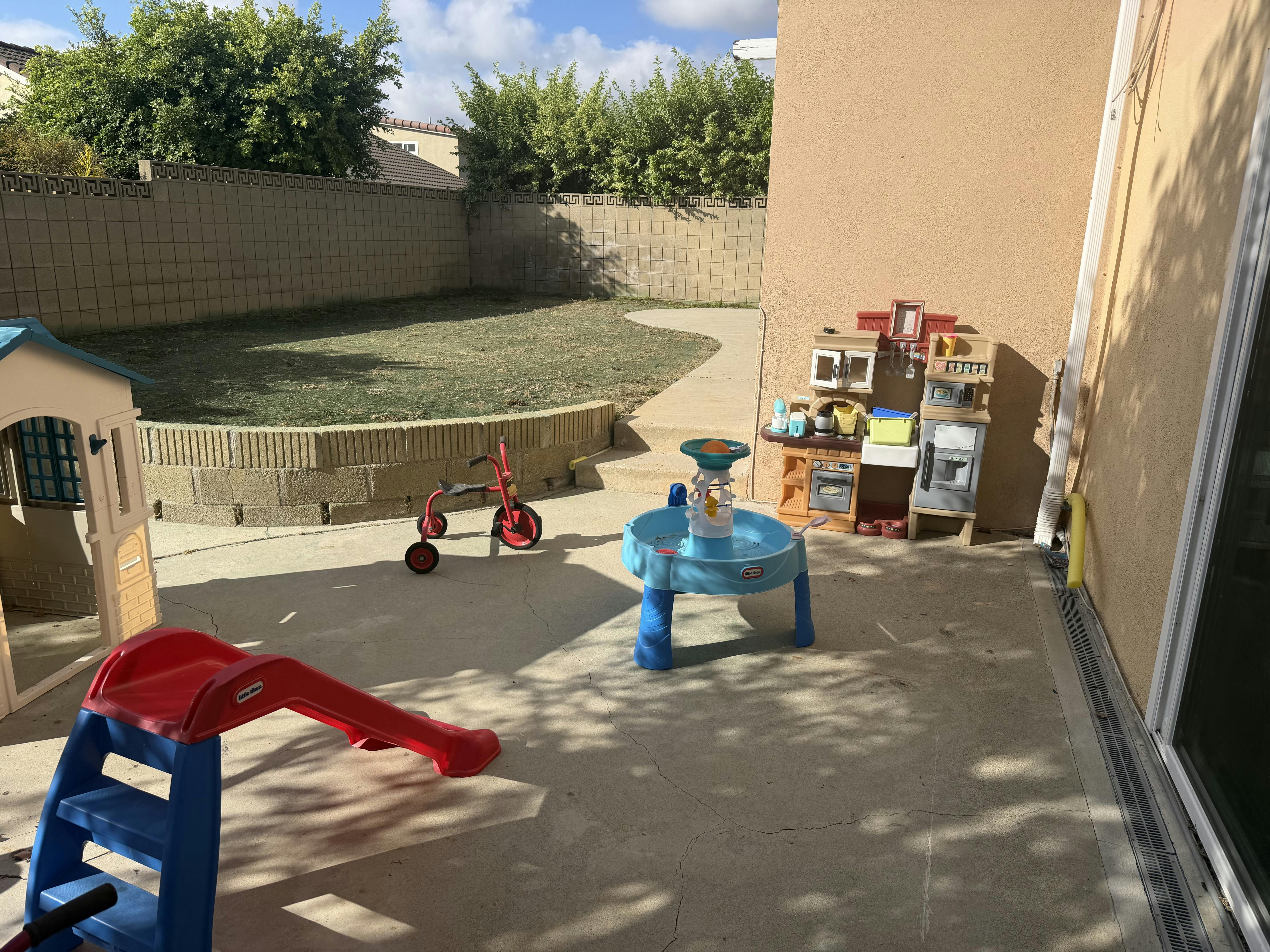 Plastic play equipment including a slide and kitchen set in a backyard patio