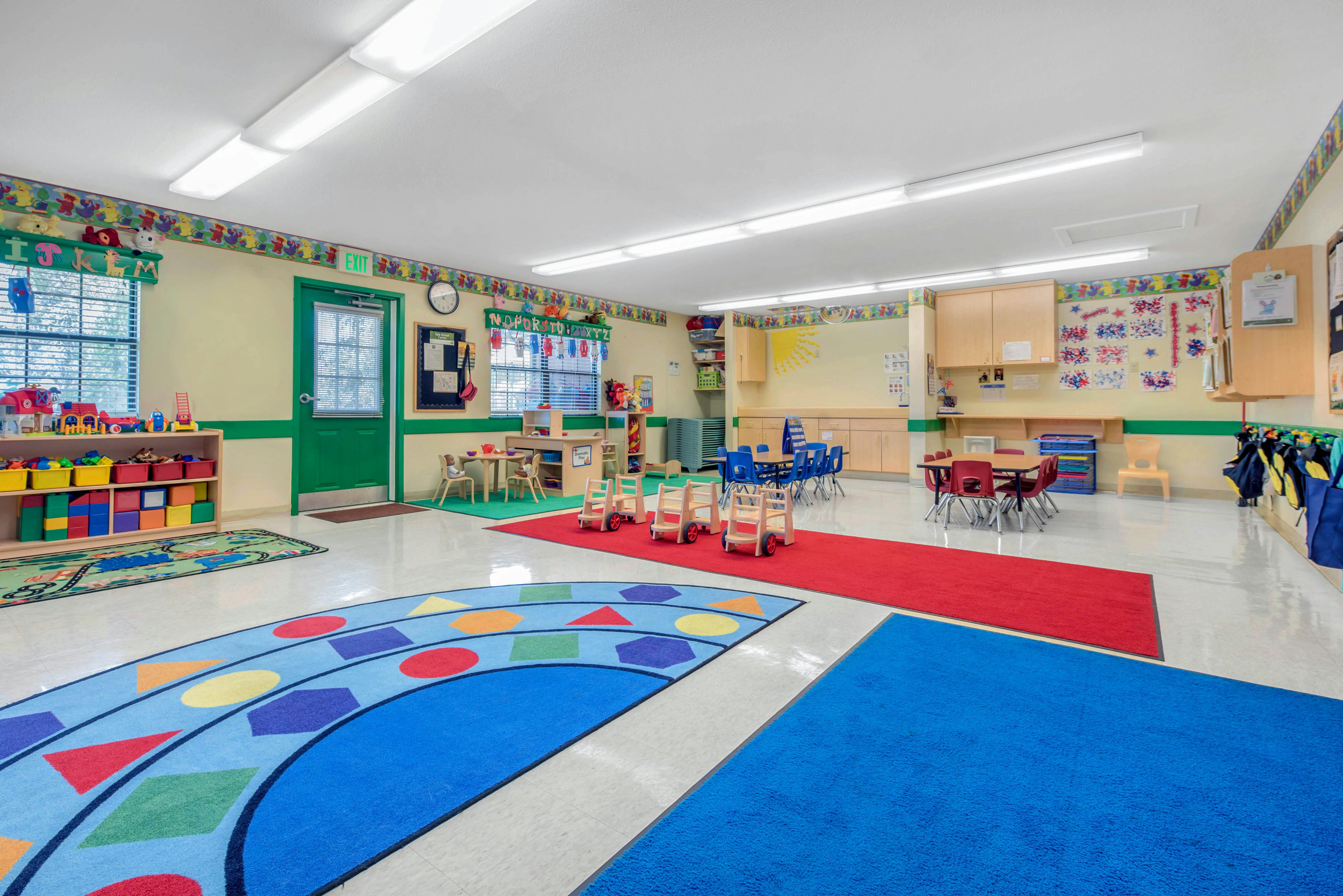 A colorful kindergarten classroom with small tables, chairs, and play areas