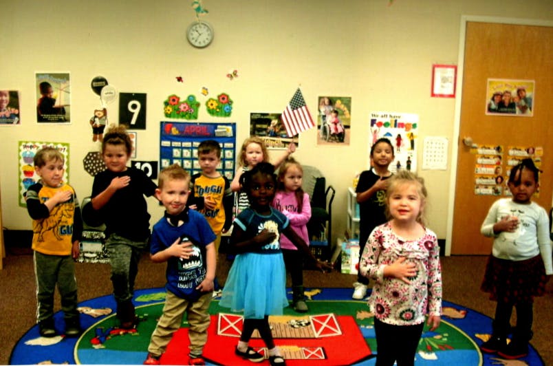 Children standing with hands over their hearts in a classroom