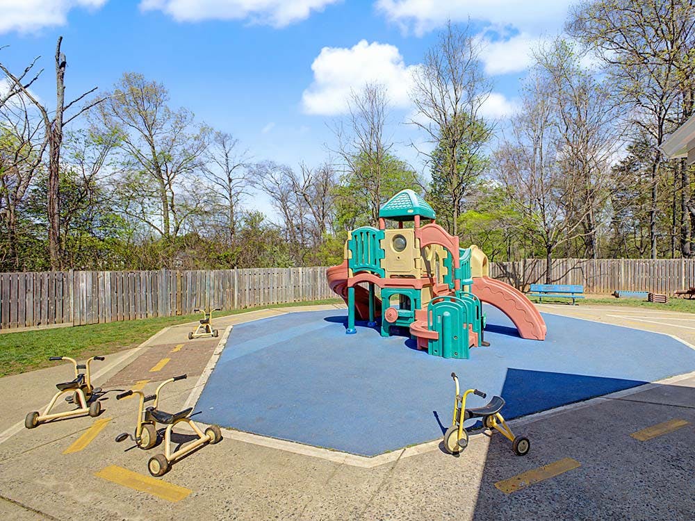 Playground with a play structure, slides, and tricycles on a blue surface
