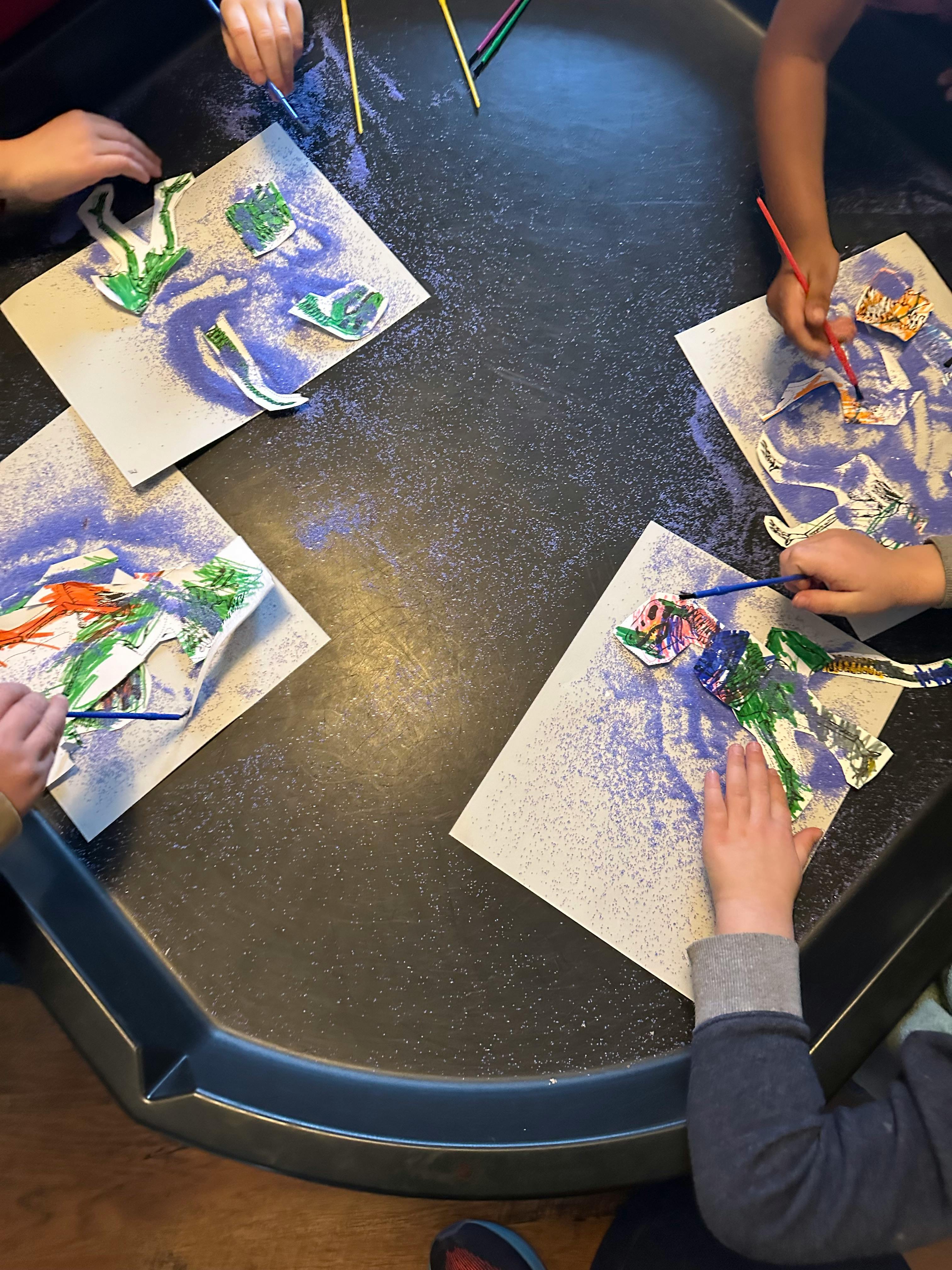 Children's hands working on art projects with glitter and cutouts