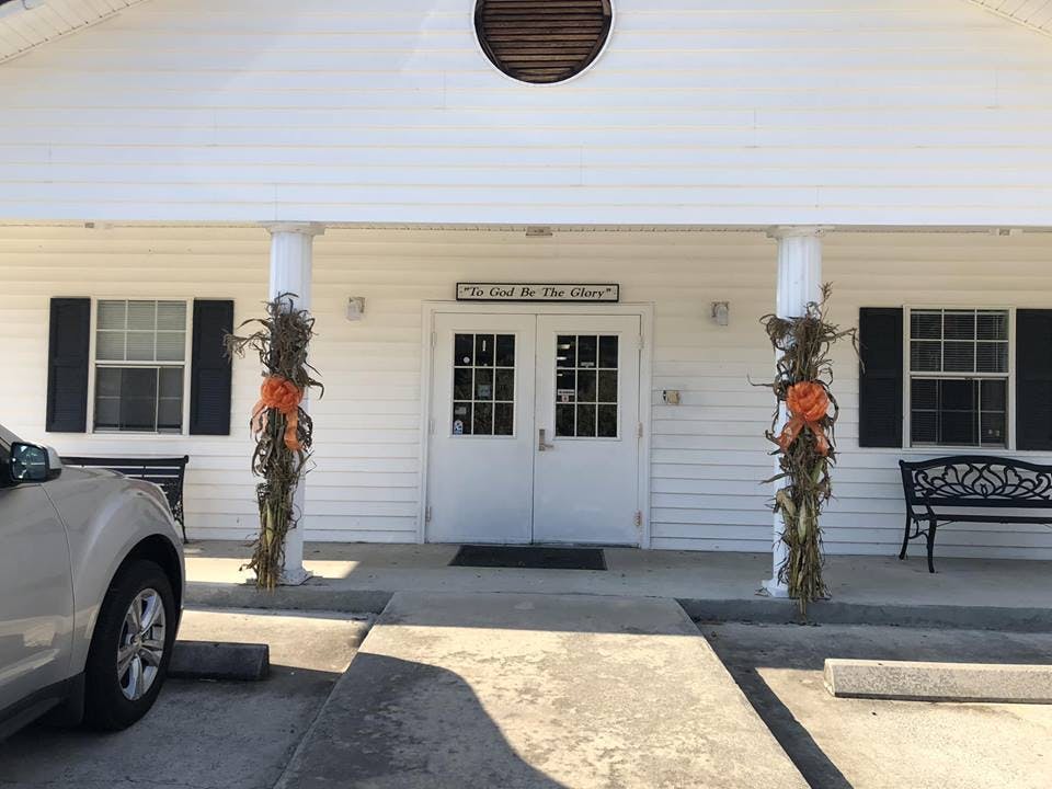 Front entrance of a white building with double doors and decorative pillars