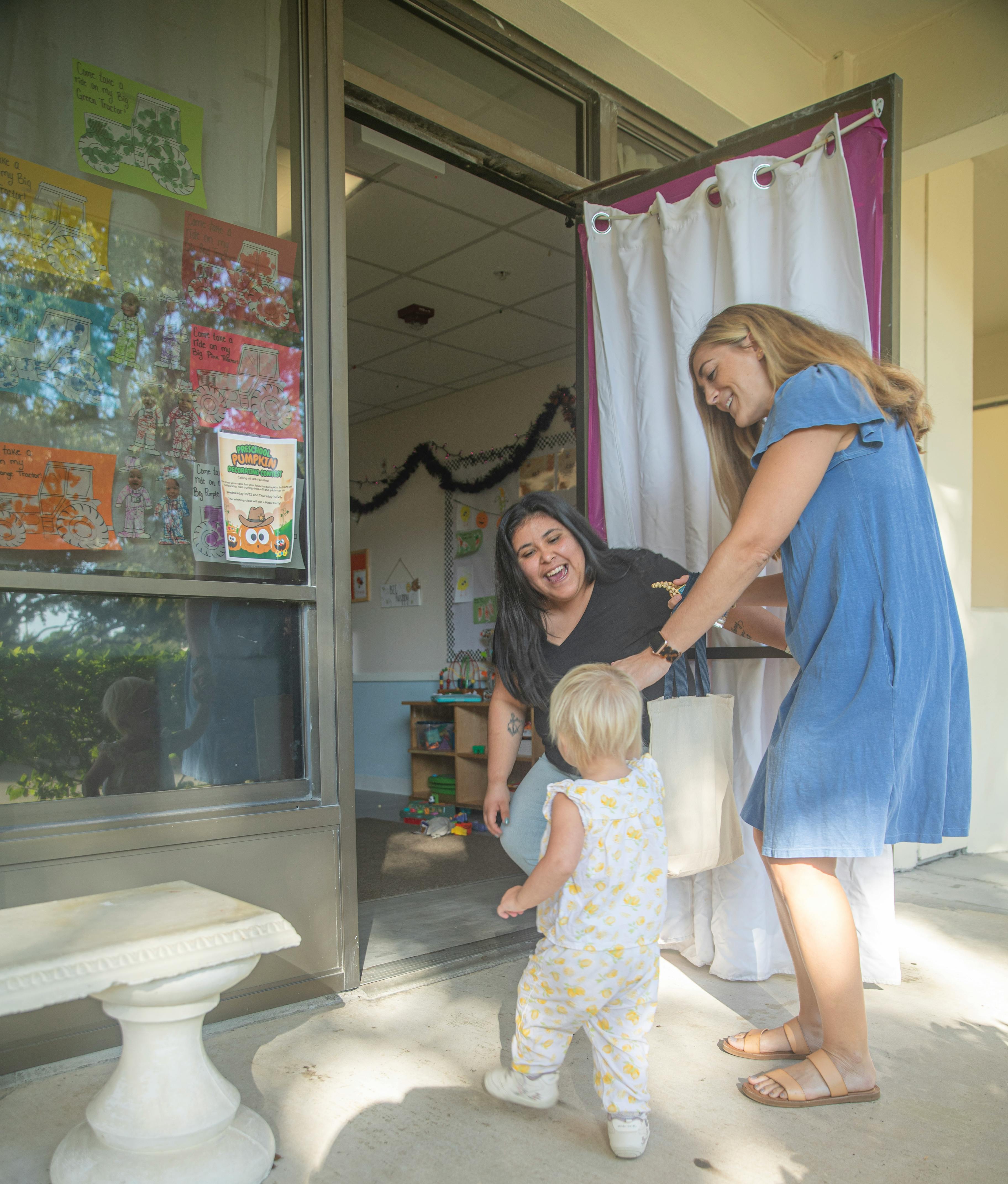 People greeting a child at the entrance of a classroom