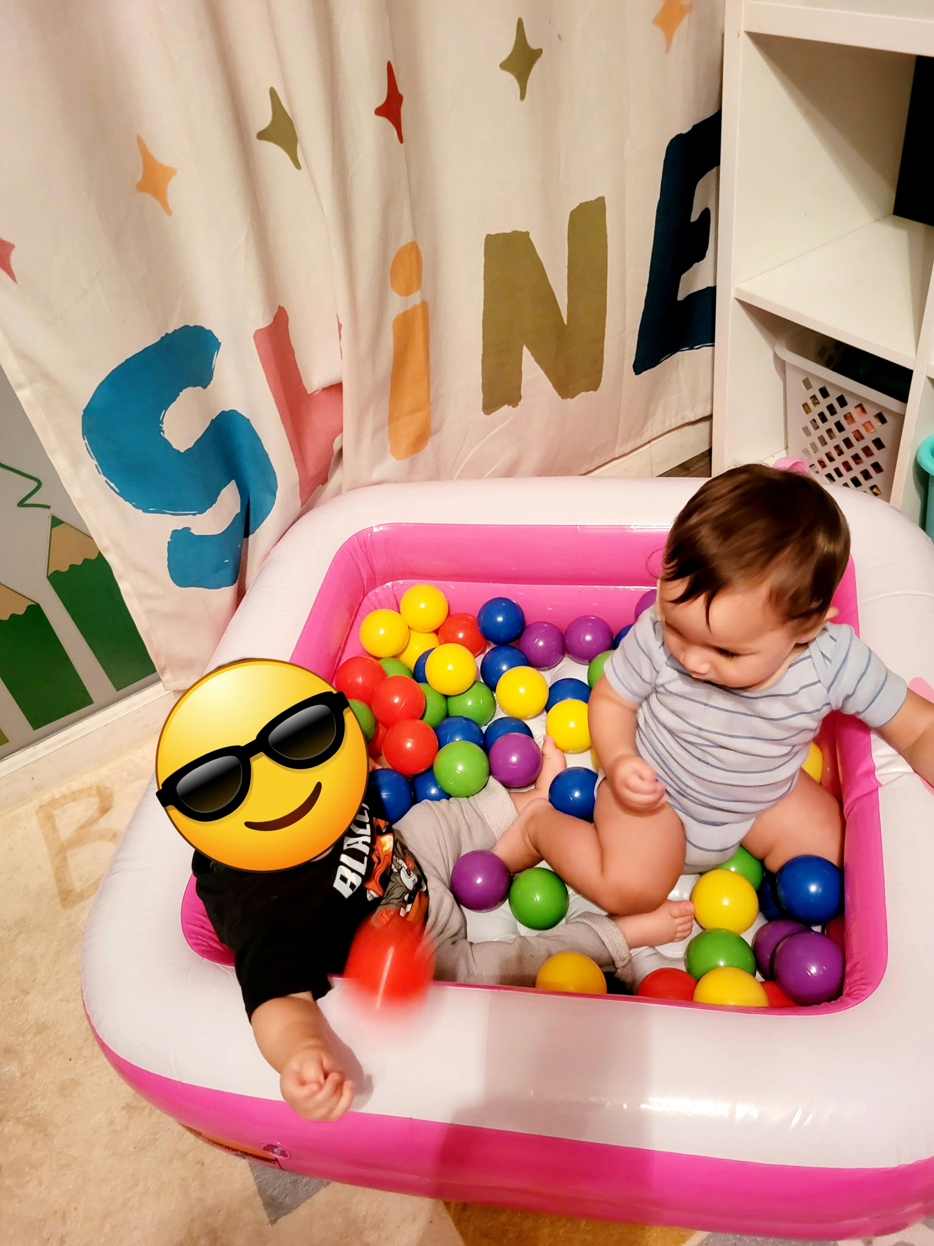 Two children playing in a pink inflatable ball pit