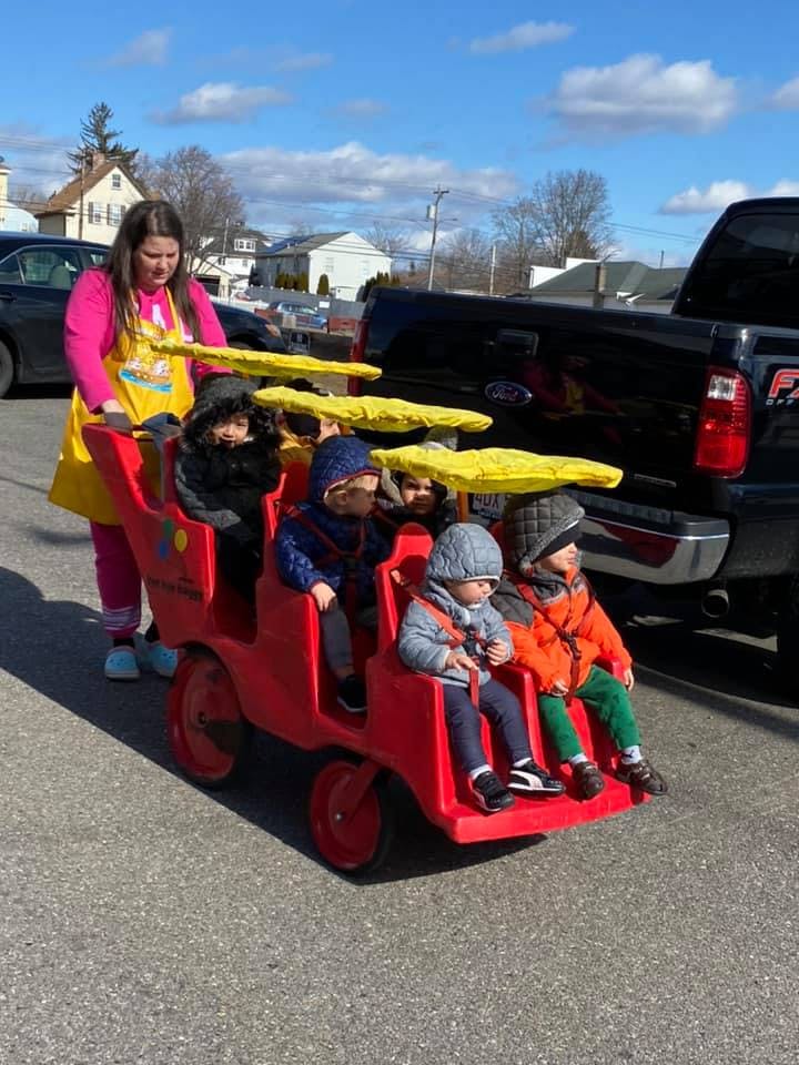 Person pushing multiple children in a red multi-seat stroller