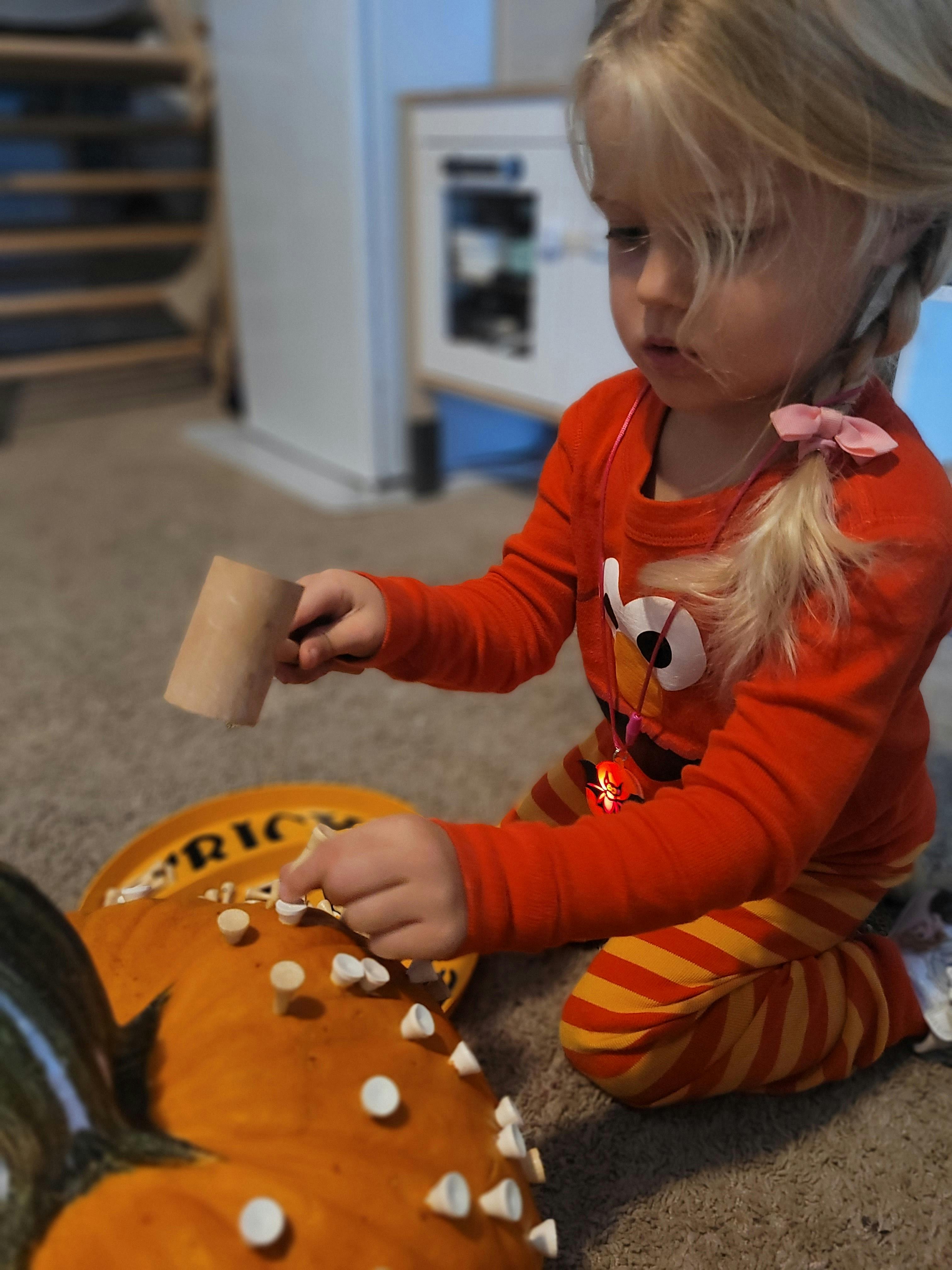 Child hammering pegs into a pumpkin