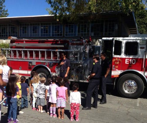 Firefighters showing a fire truck to a group of children