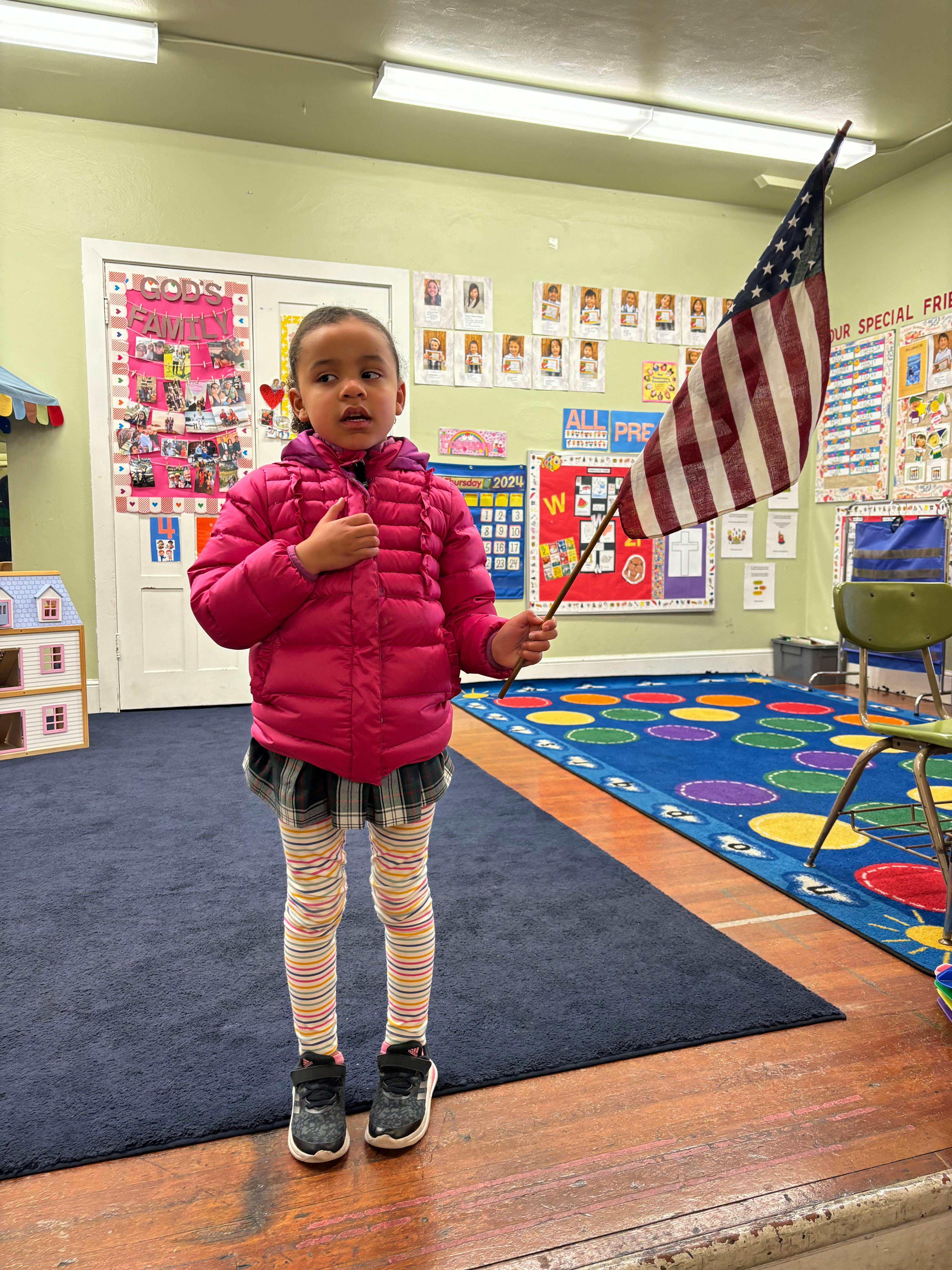 Child in a classroom holding a small American flag