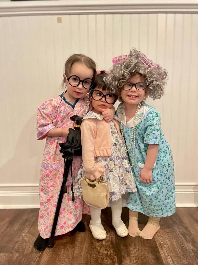 Three children in old-age costumes with glasses, wigs, and accessories