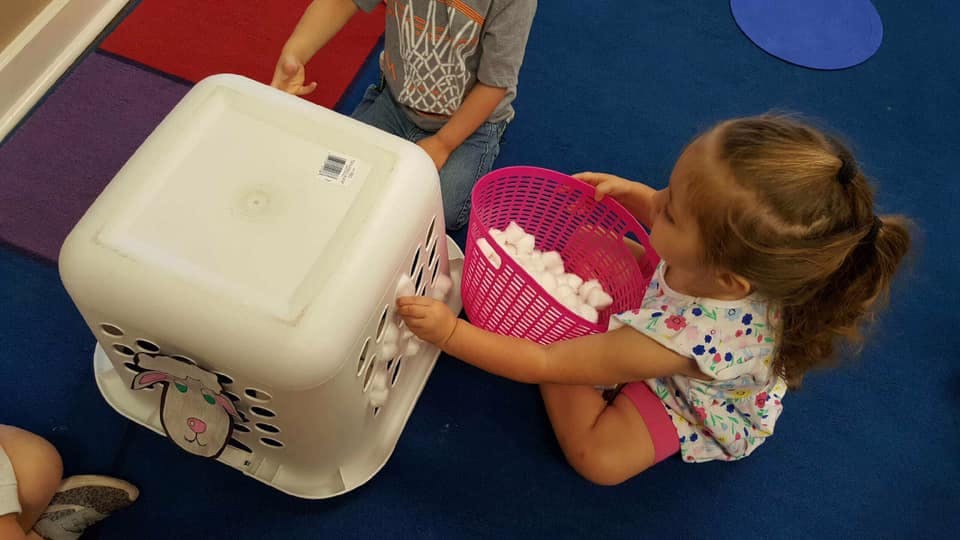 Child playing with a laundry basket and a pink container