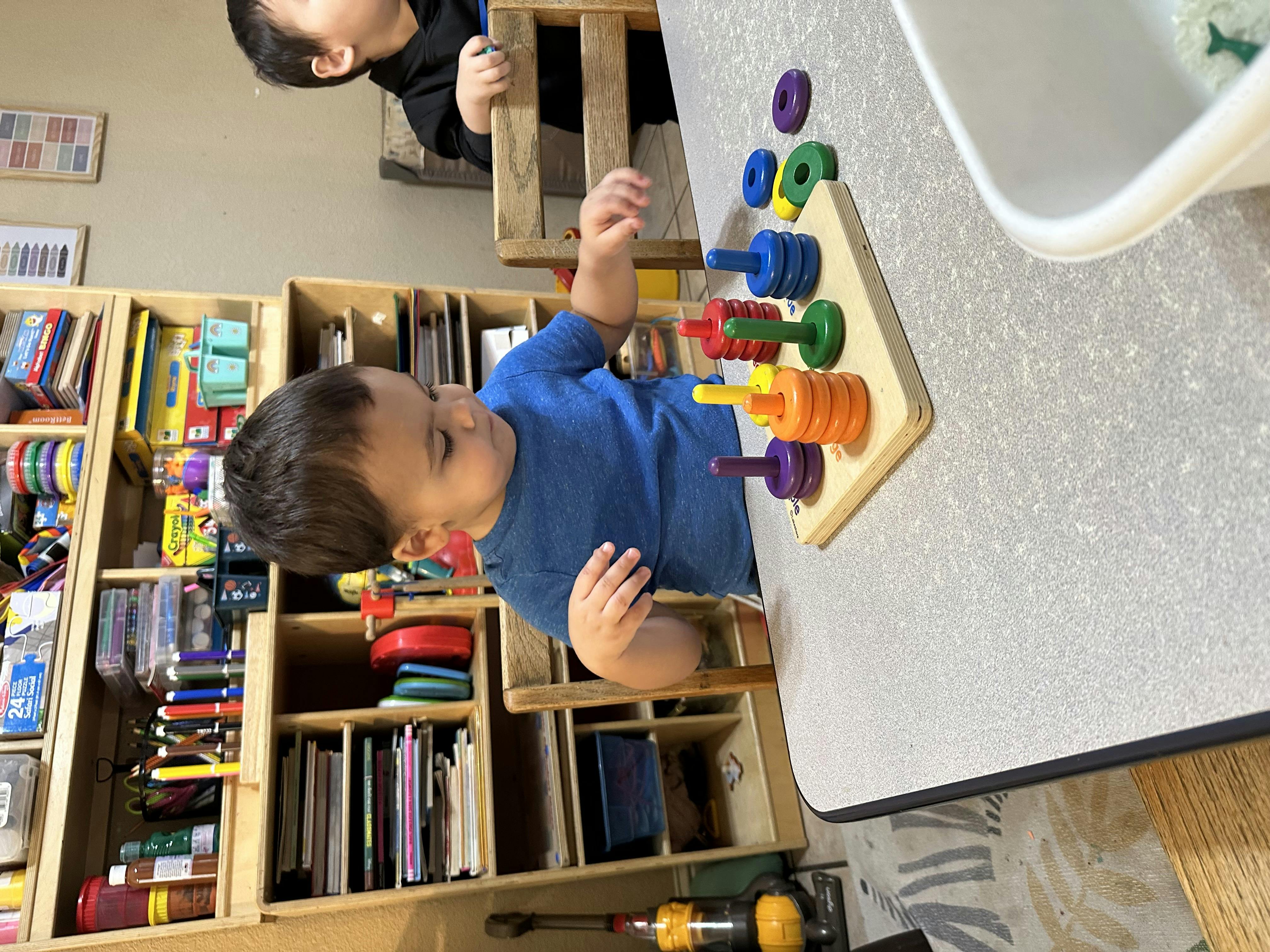 Child playing with a colorful stacking toy on a table