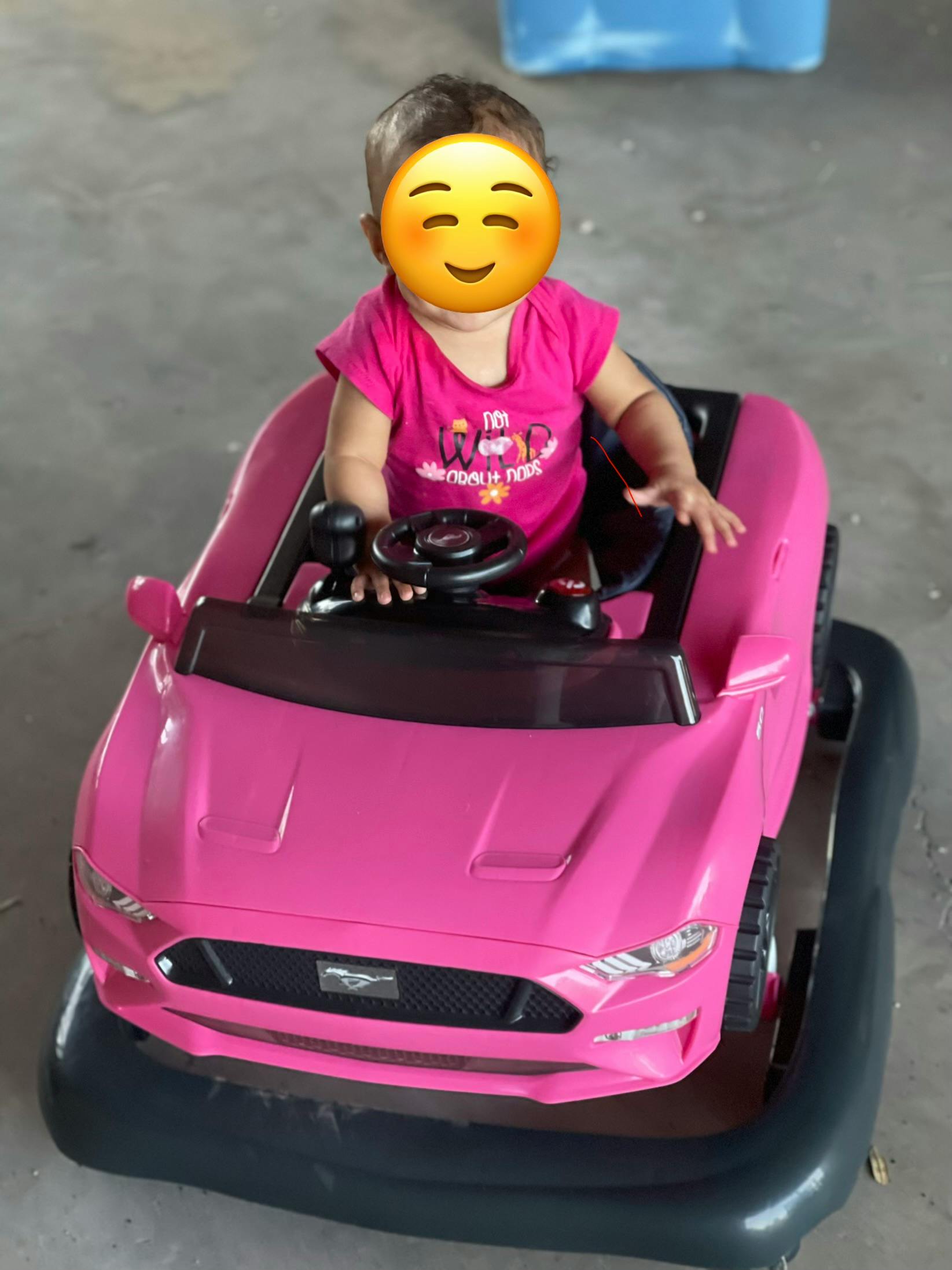 Child sitting in a pink toy car