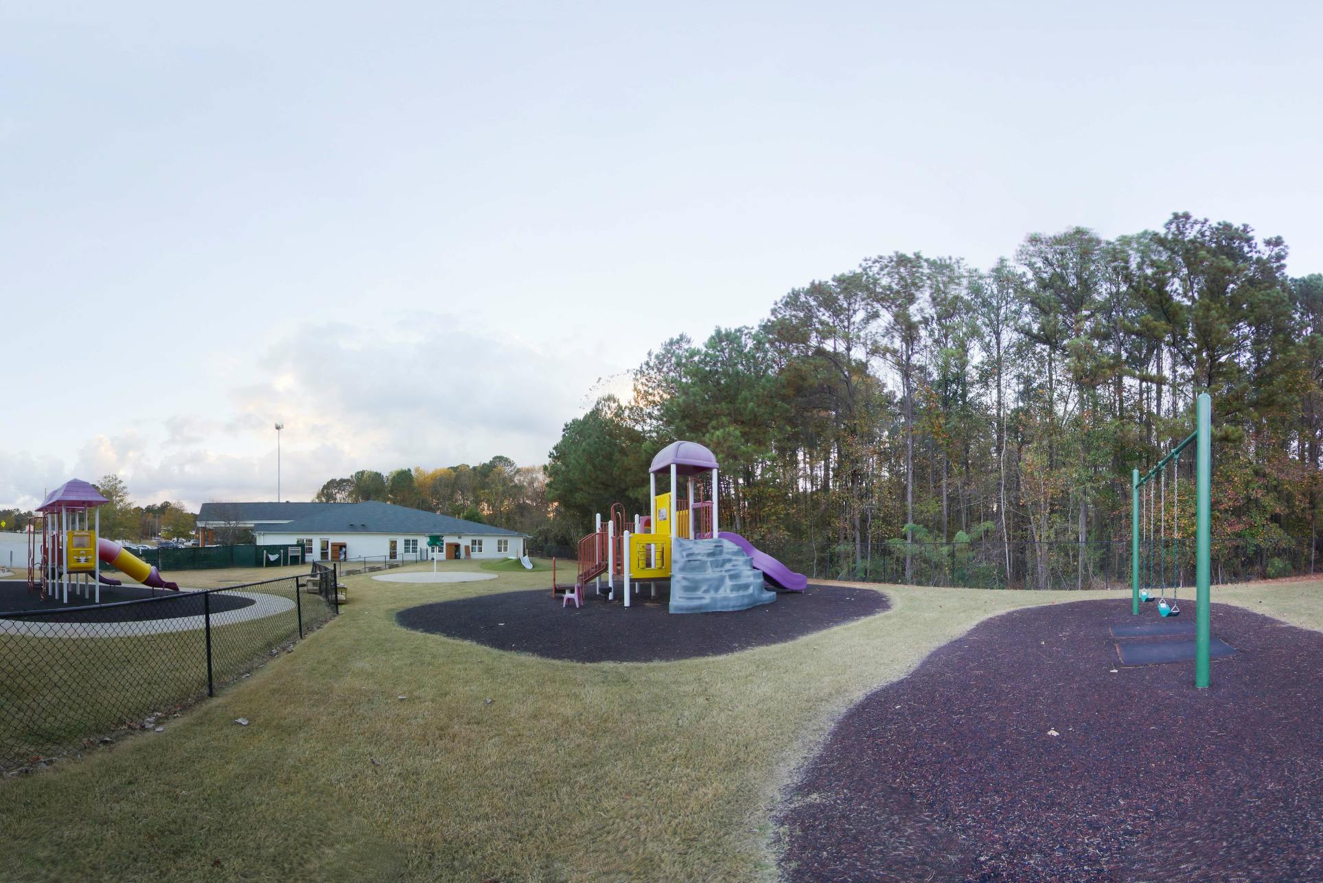 Playground with swings, slides, climbing structure, and a building in the background