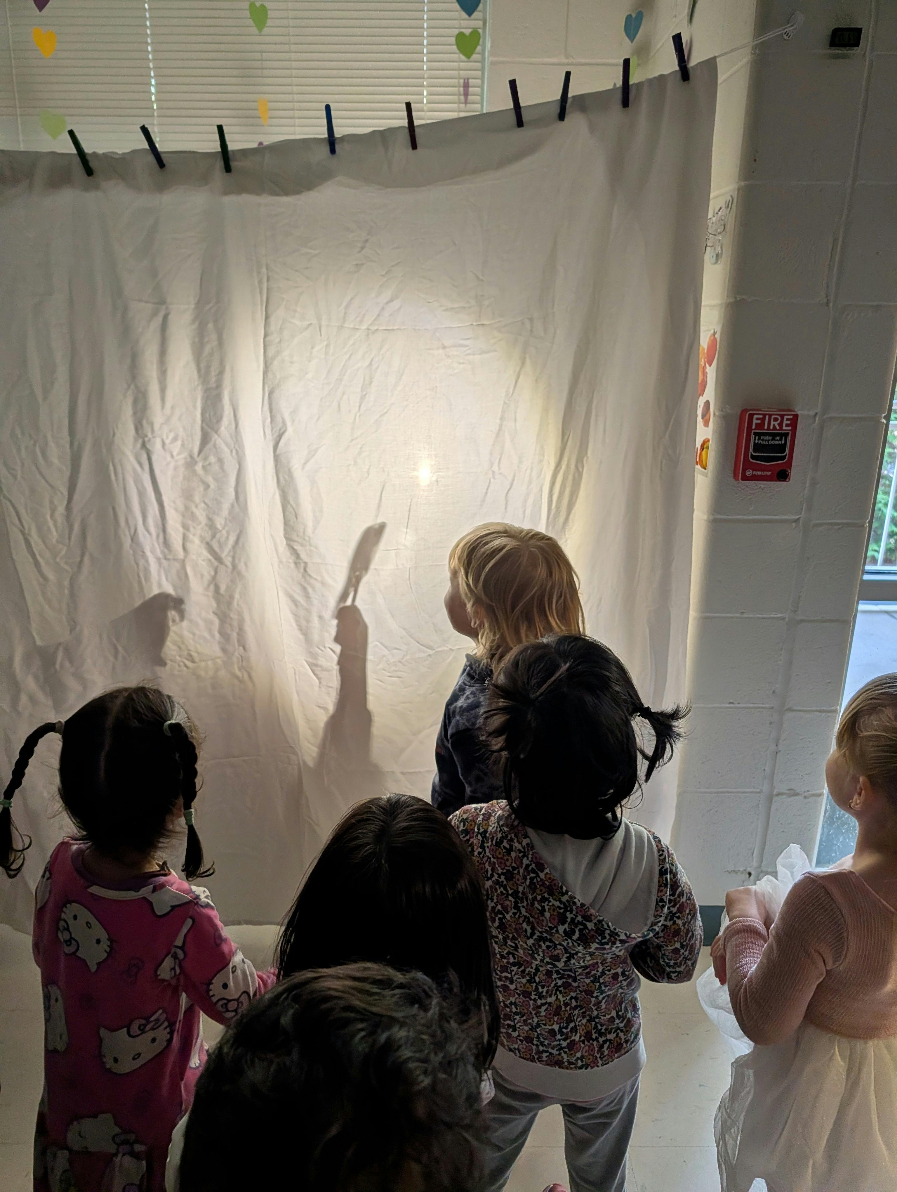 Children watching shadows on a white sheet