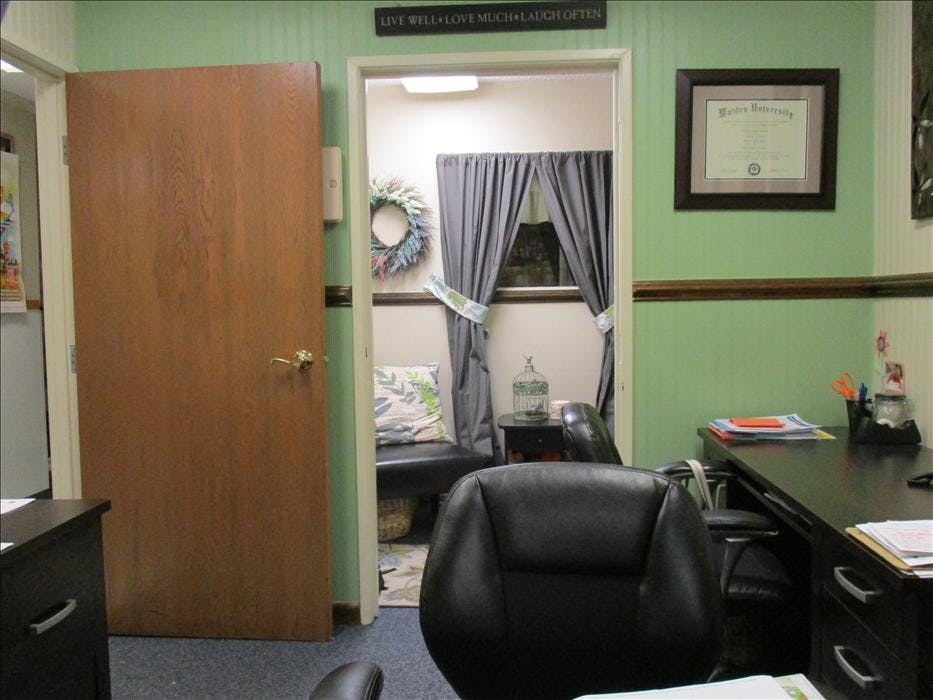 Office with a partial door, a doorway leading to a small waiting area, and a desk