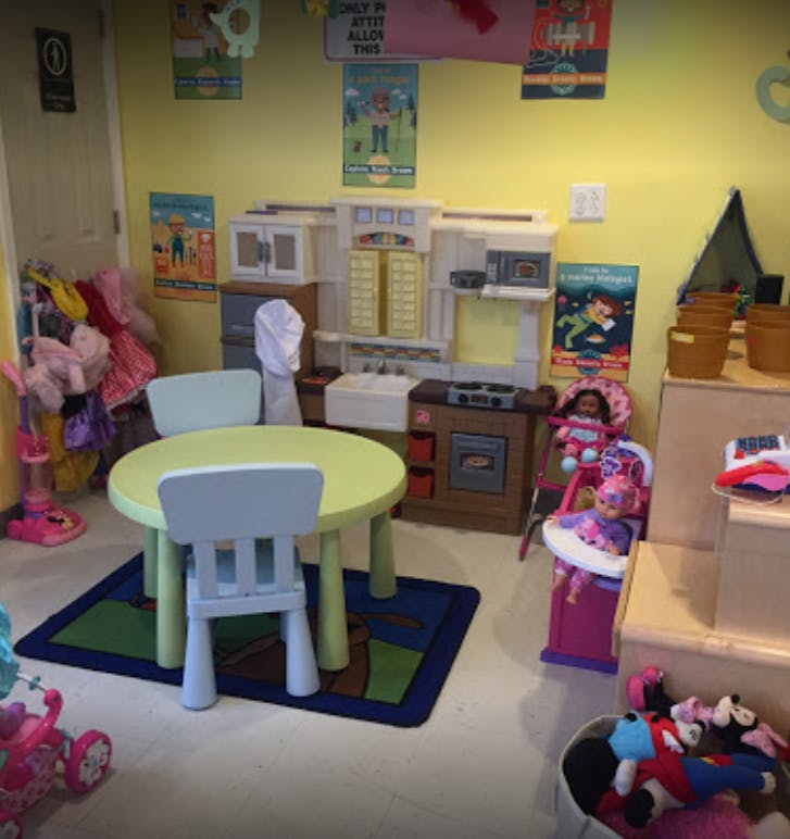Playroom with a small table and chairs, toy kitchen, and dolls