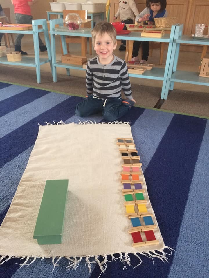 Child kneeling on a rug with a mat and colorful blocks