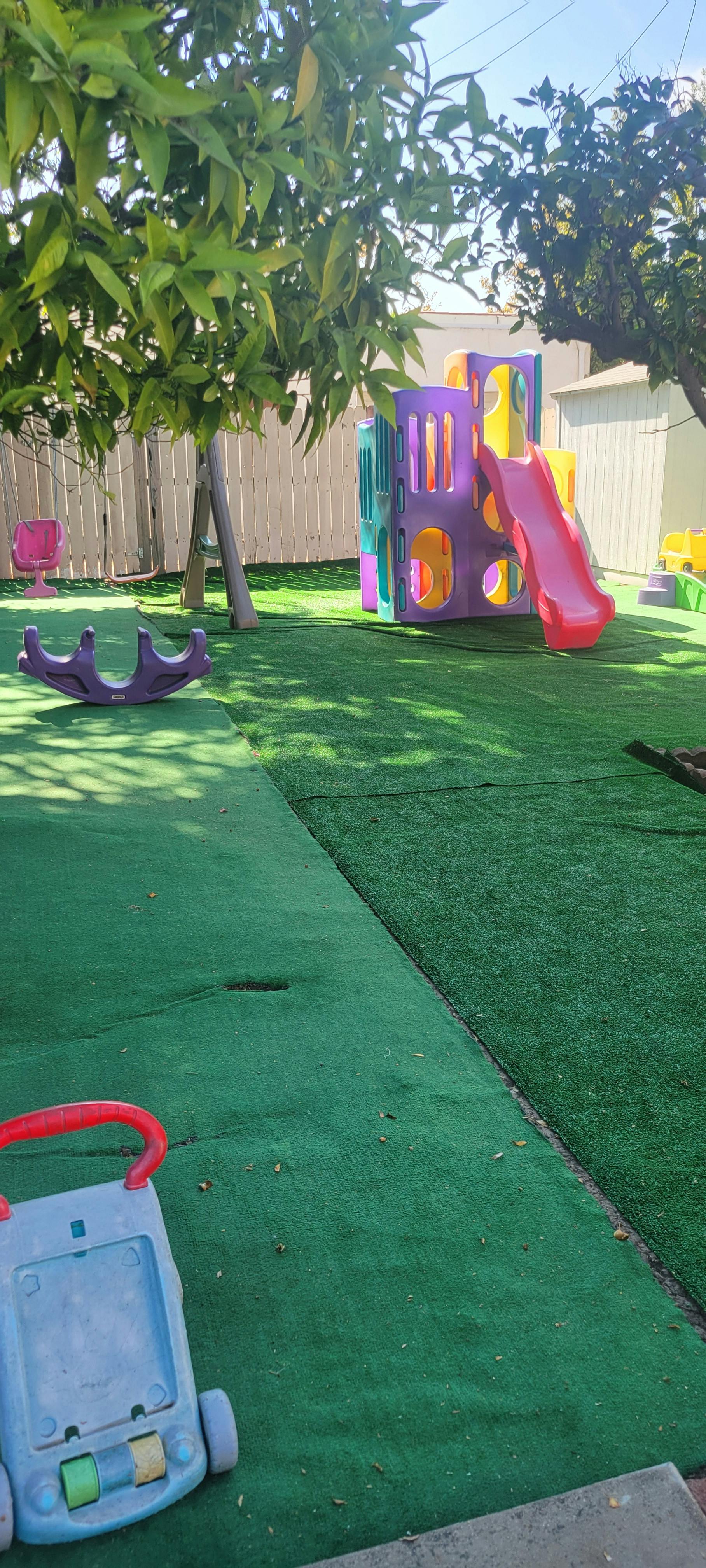 Colorful plastic play structure and toys on artificial grass in a backyard