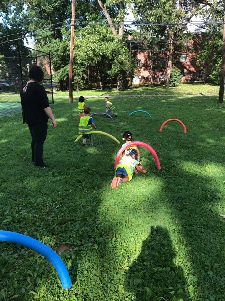 Adult and children playing with colorful hoops on a grassy field