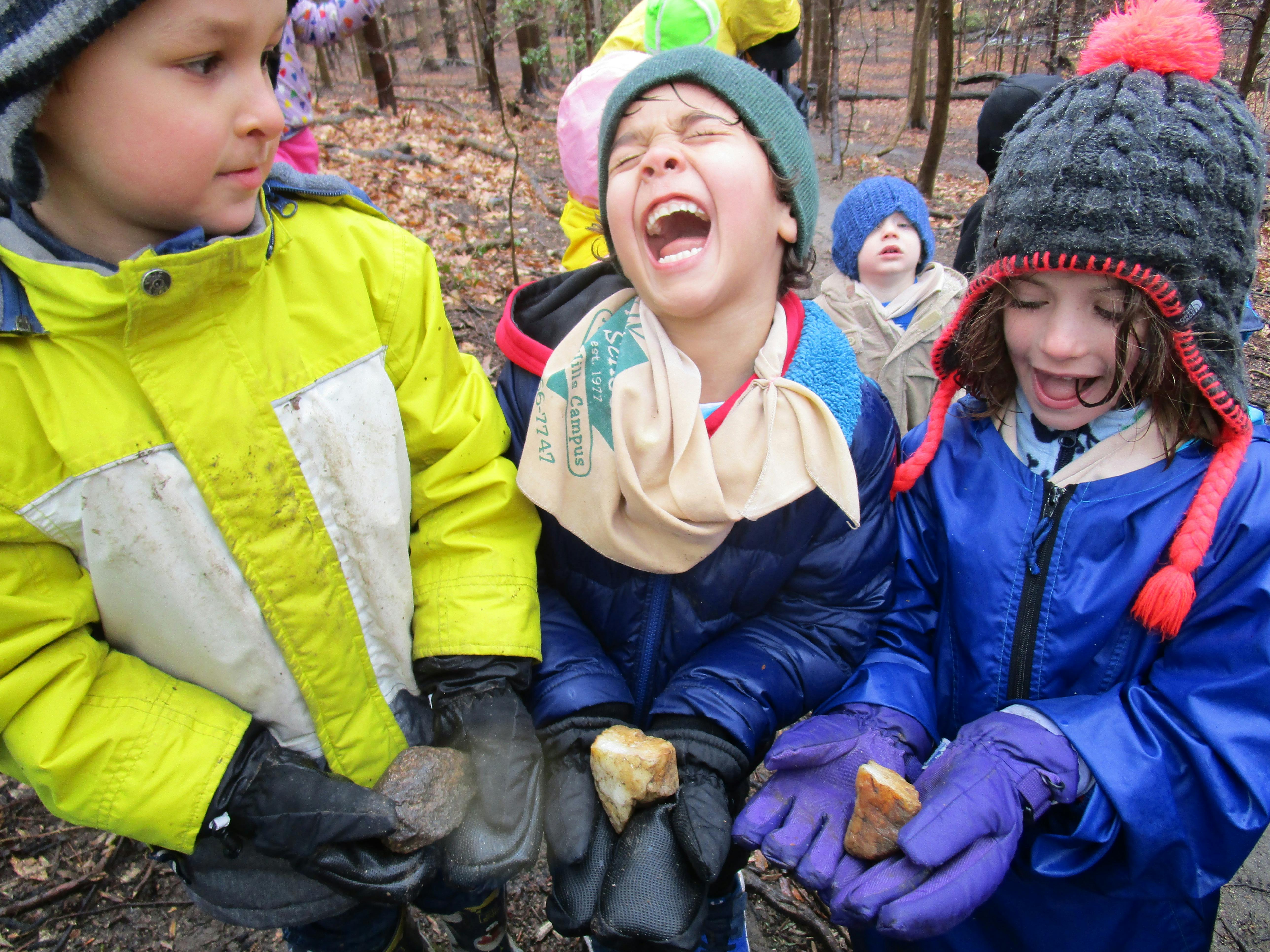 Three children holding rocks outdoors