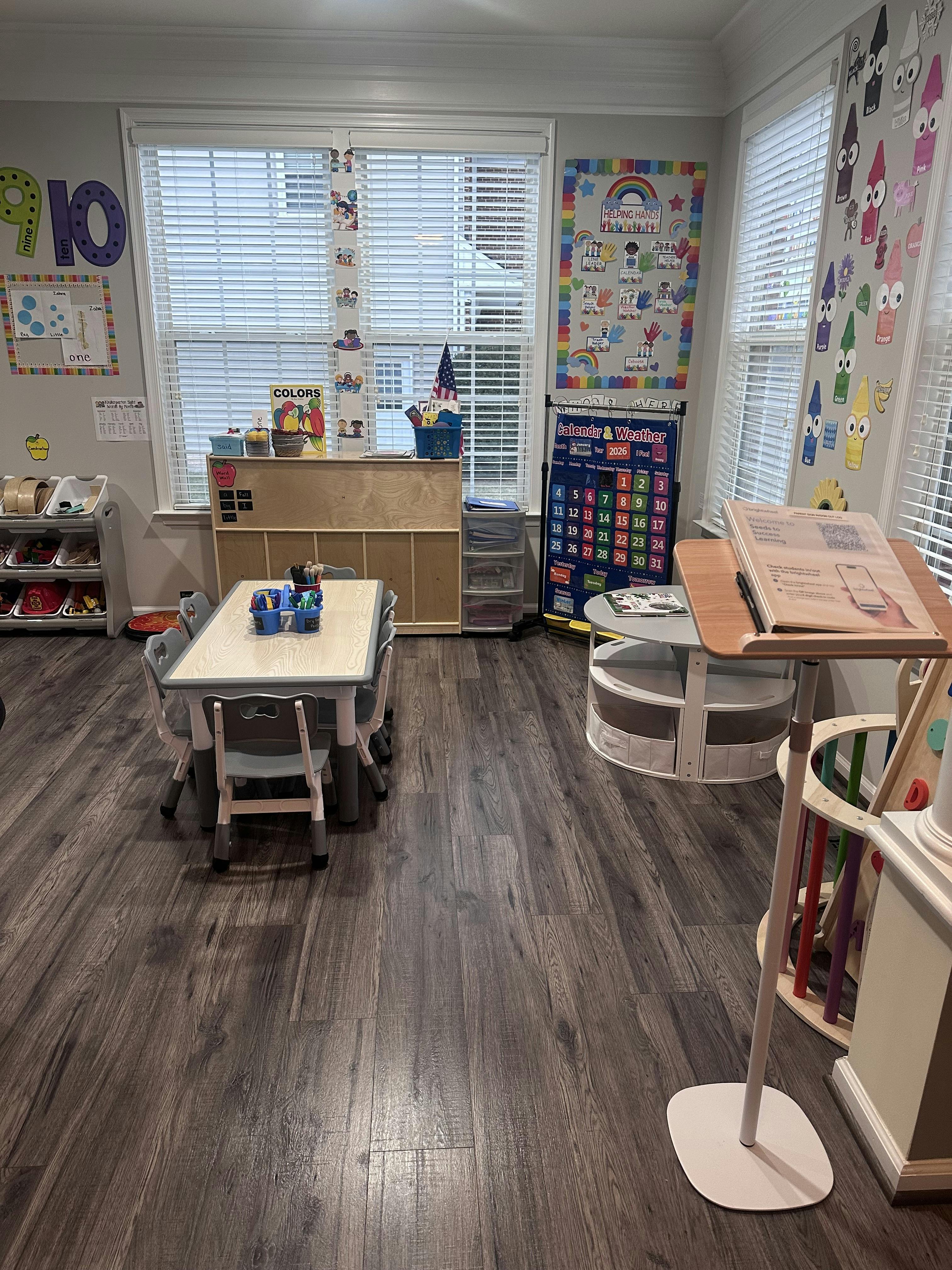 Classroom with child-sized tables and chairs, educational posters on walls and windows